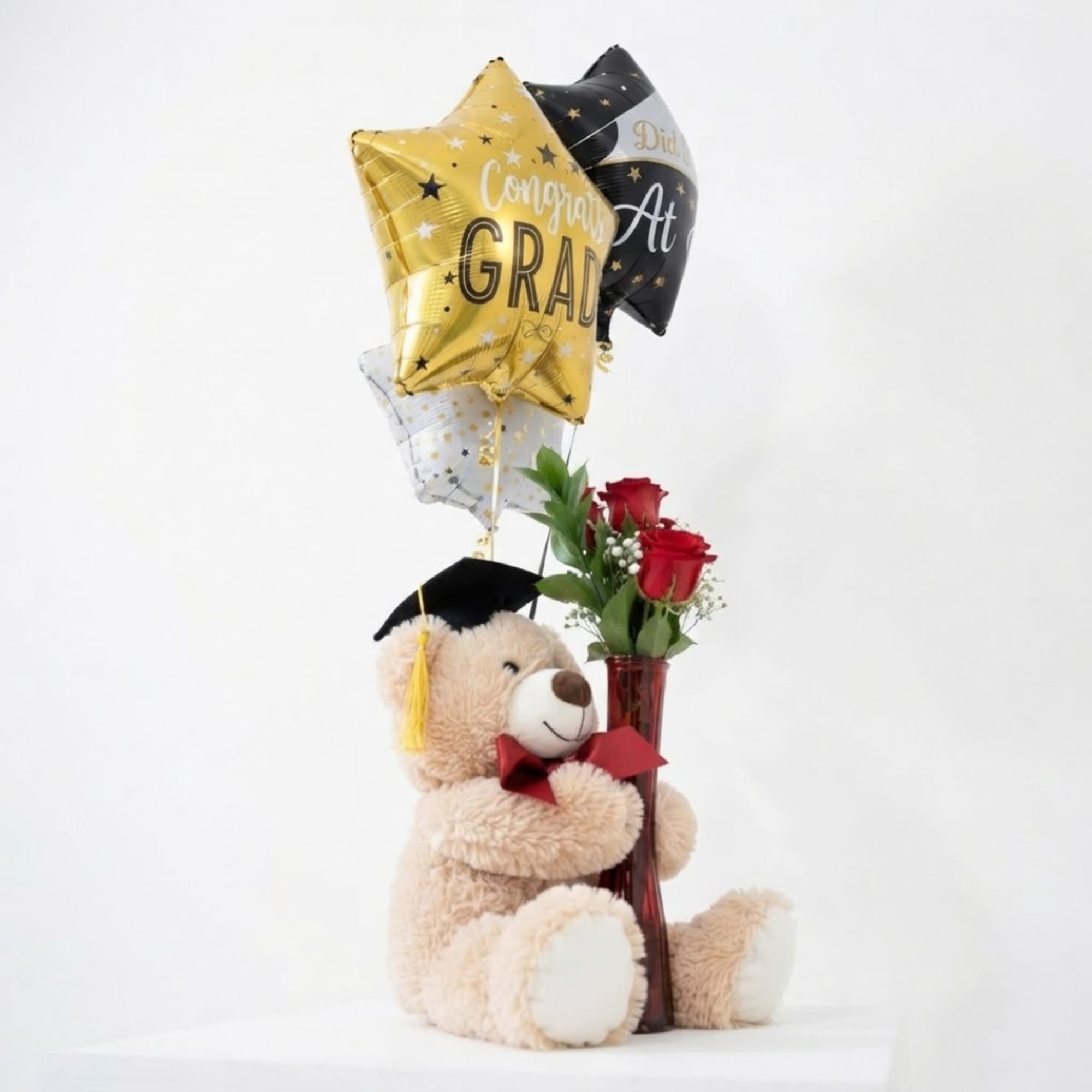 Teddy bear with graduation balloons and red roses in a vase