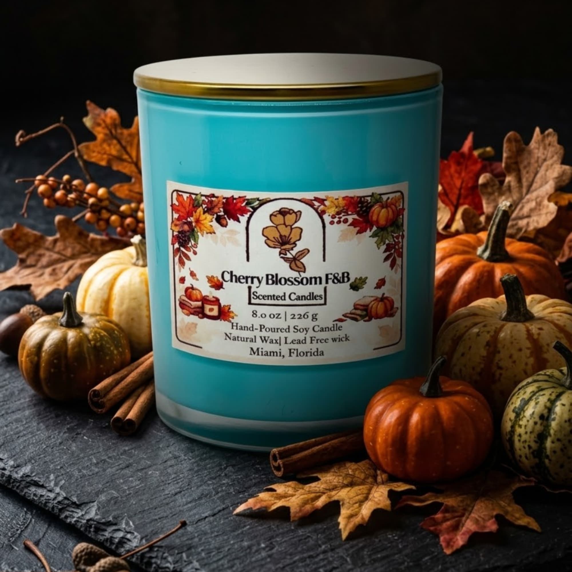 Turquoise scented candle in a jar surrounded by pumpkins and autumn leaves