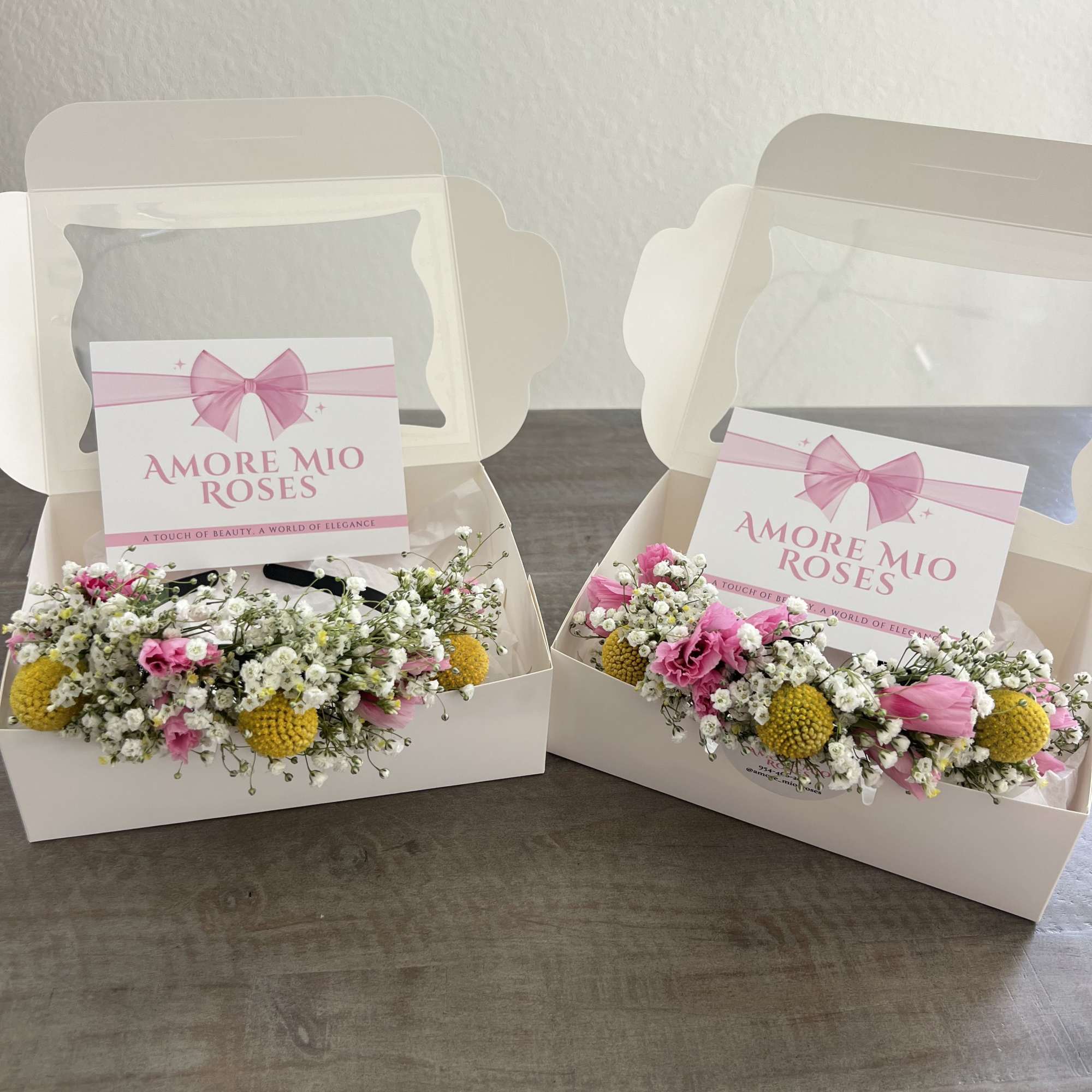 Two boxed pink and white floral arrangements with yellow accents