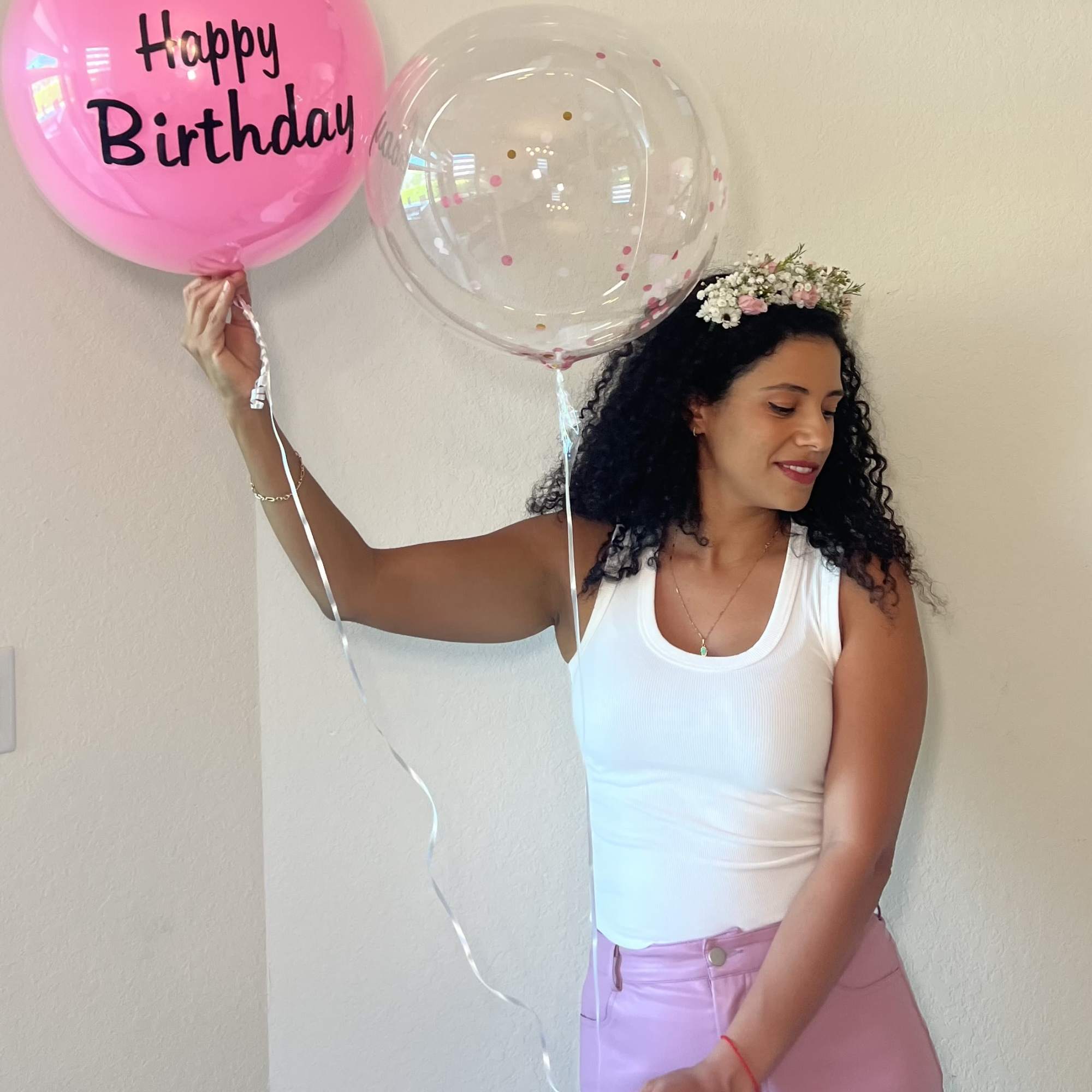 Woman holding two birthday balloons and wearing a small flower crown