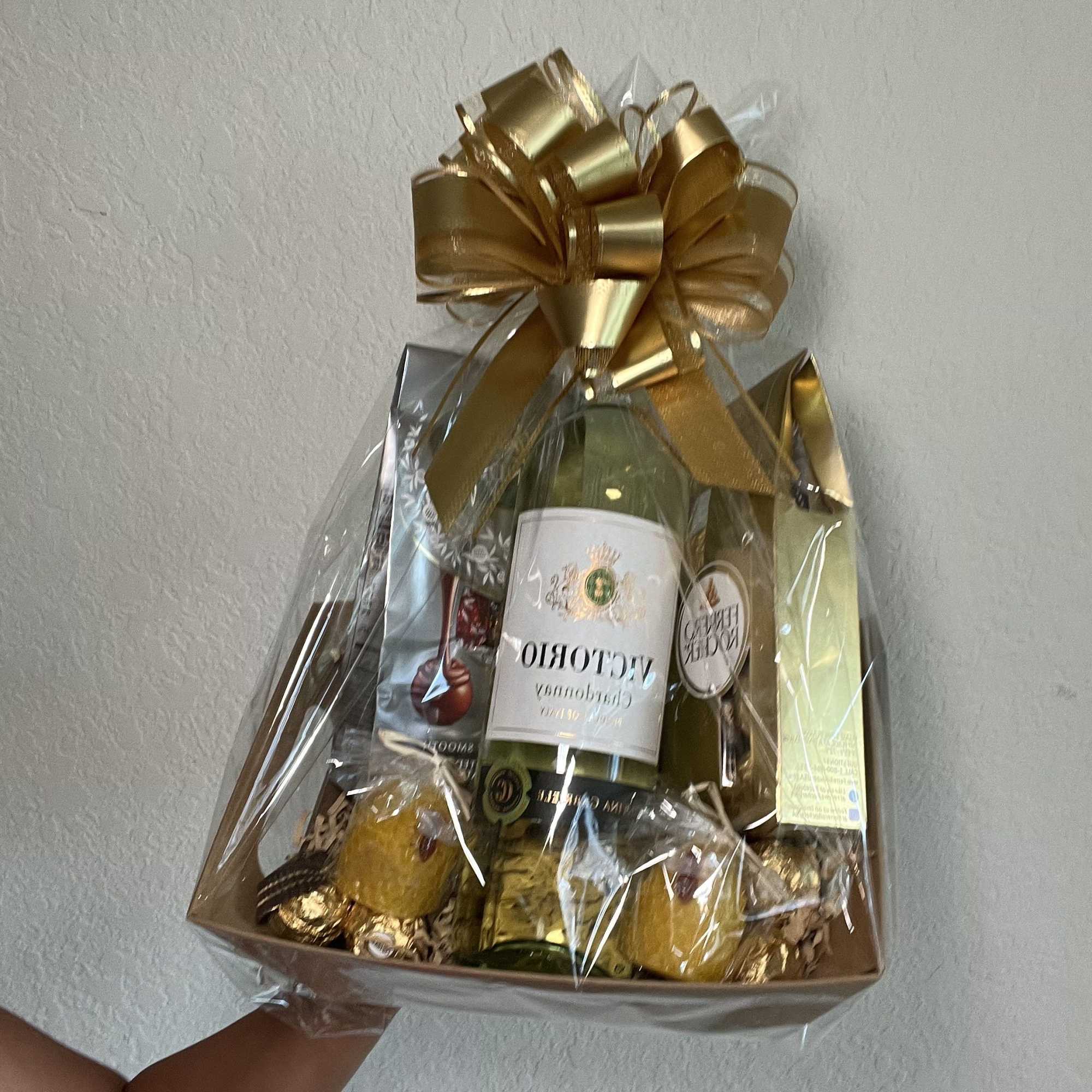 Gift basket with wine bottles, chocolates, and a gold bow