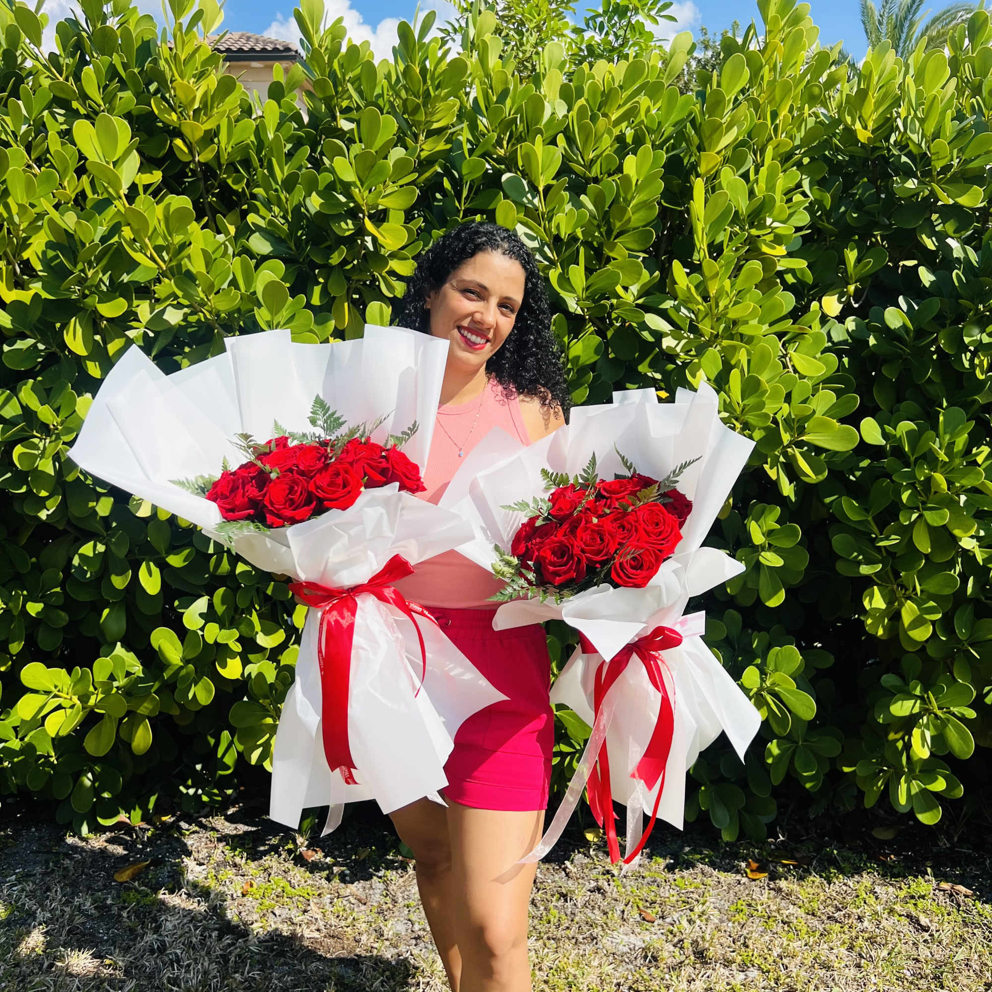 Woman holding two bouquets of red roses wrapped in white paper