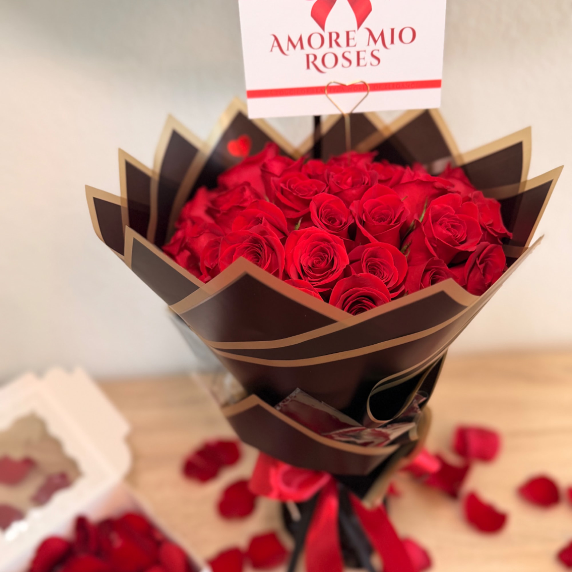 Bouquet of red roses wrapped in dark paper with a sign above it