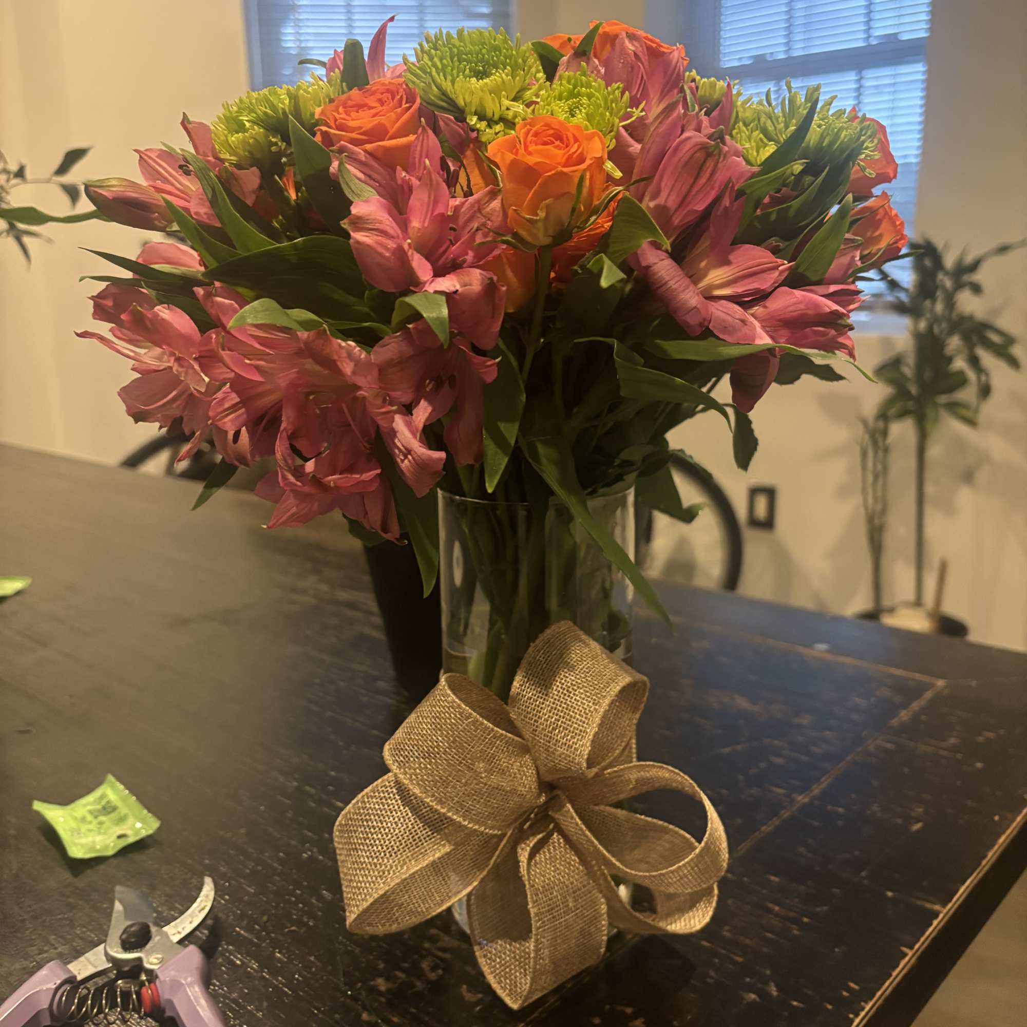 Pink and orange flowers in a glass vase with a burlap bow