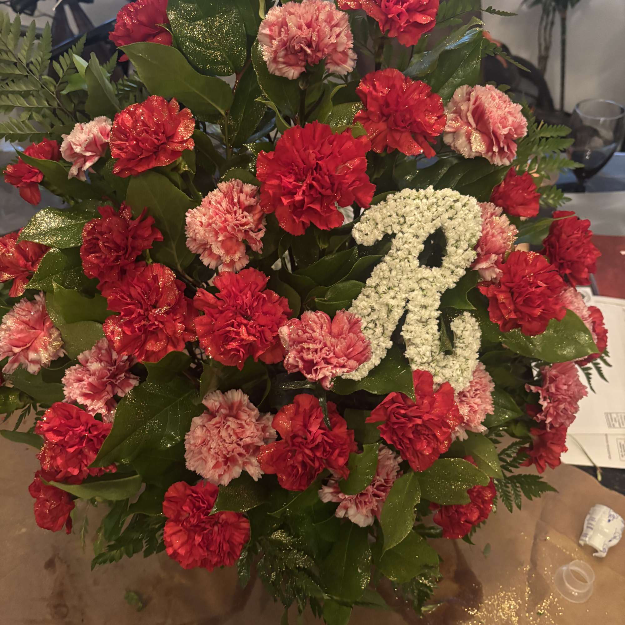 Red and pink carnation arrangement with a white ribbon accent