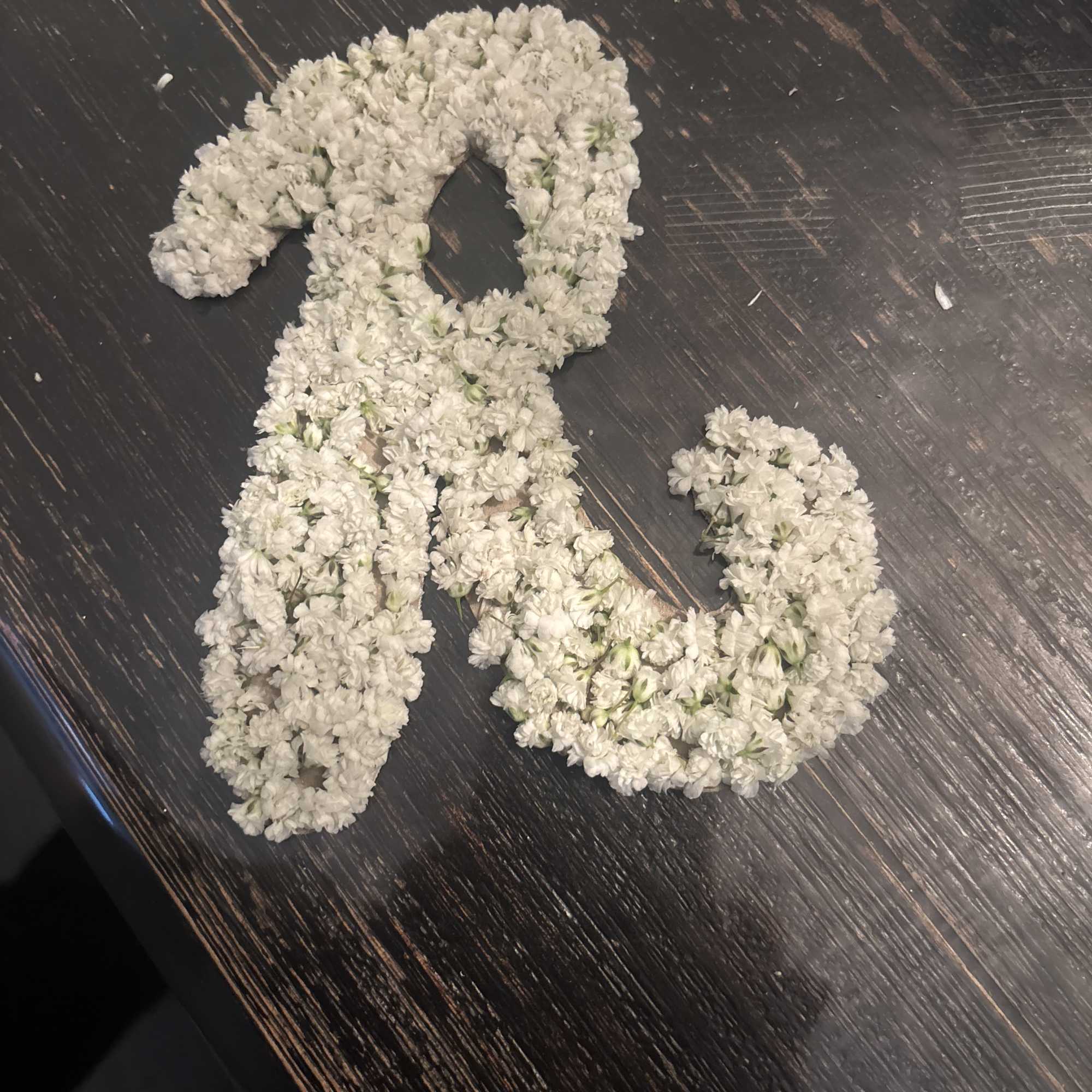 White floral garland arranged in a loop on a dark wooden surface