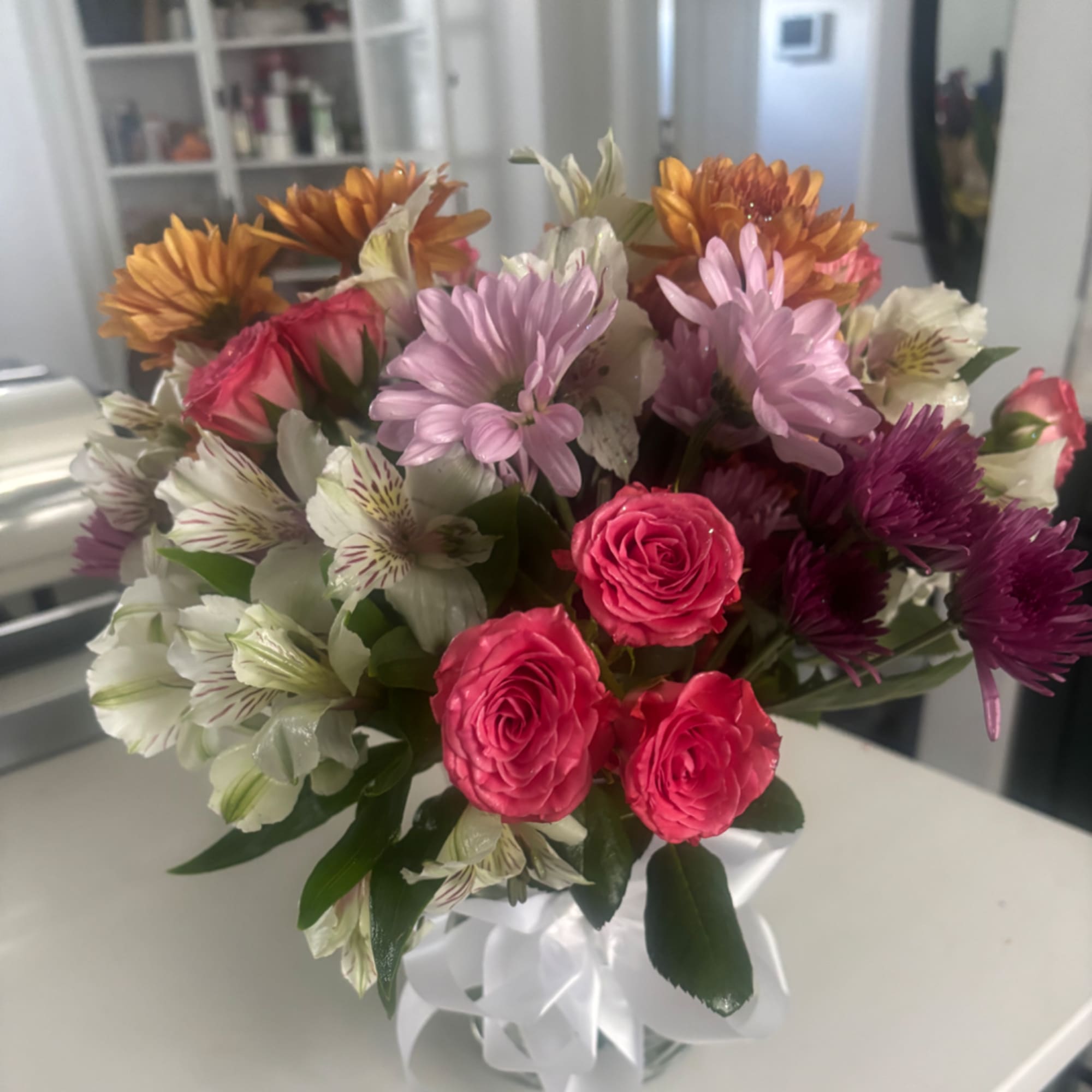 Mixed bouquet of pink roses, chrysanthemums, and white alstroemeria in a vase