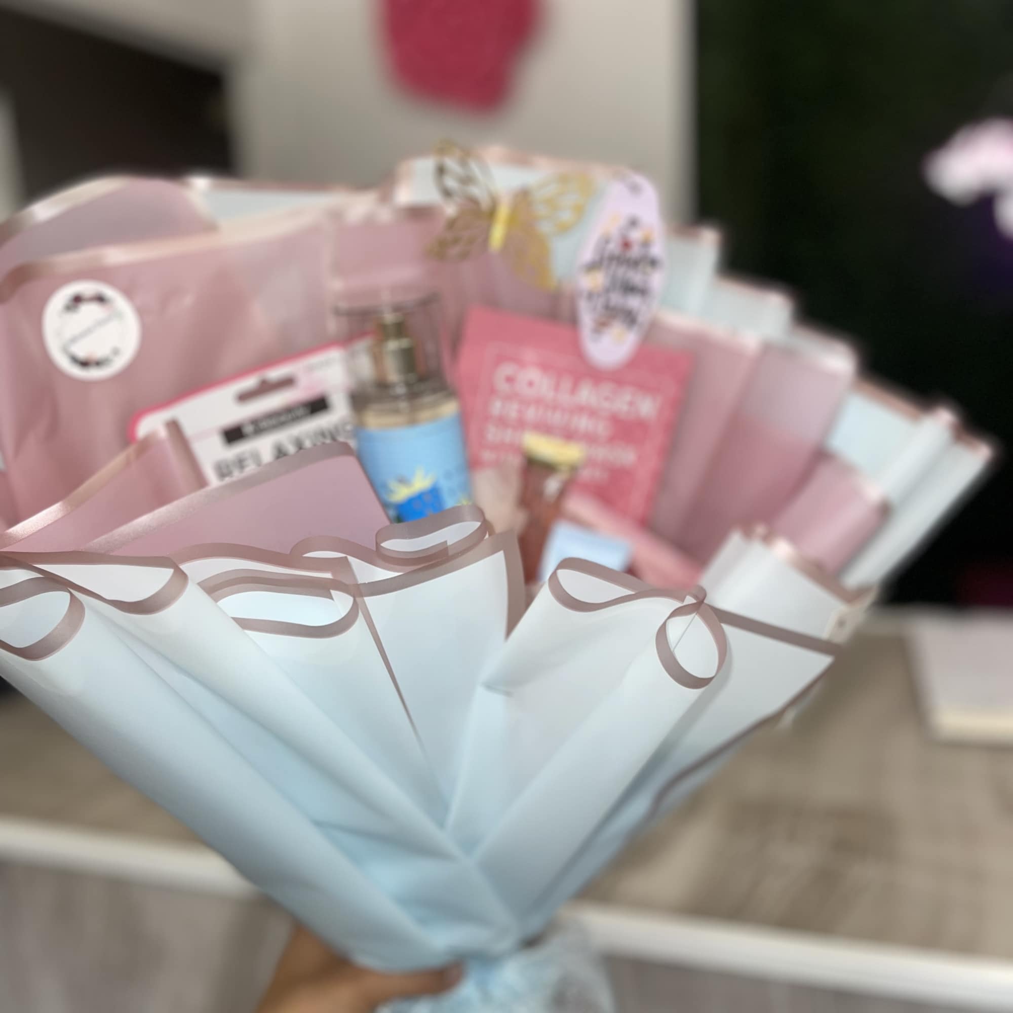 A pastel gift bouquet with skincare items wrapped in pink and blue paper
