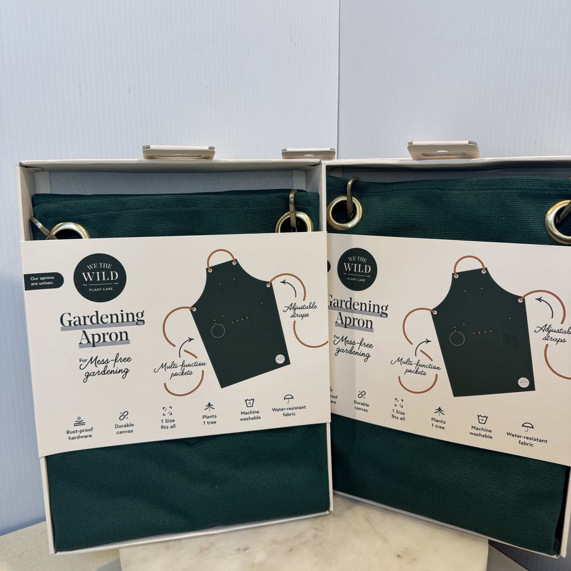 Two boxed green gardening aprons on a table