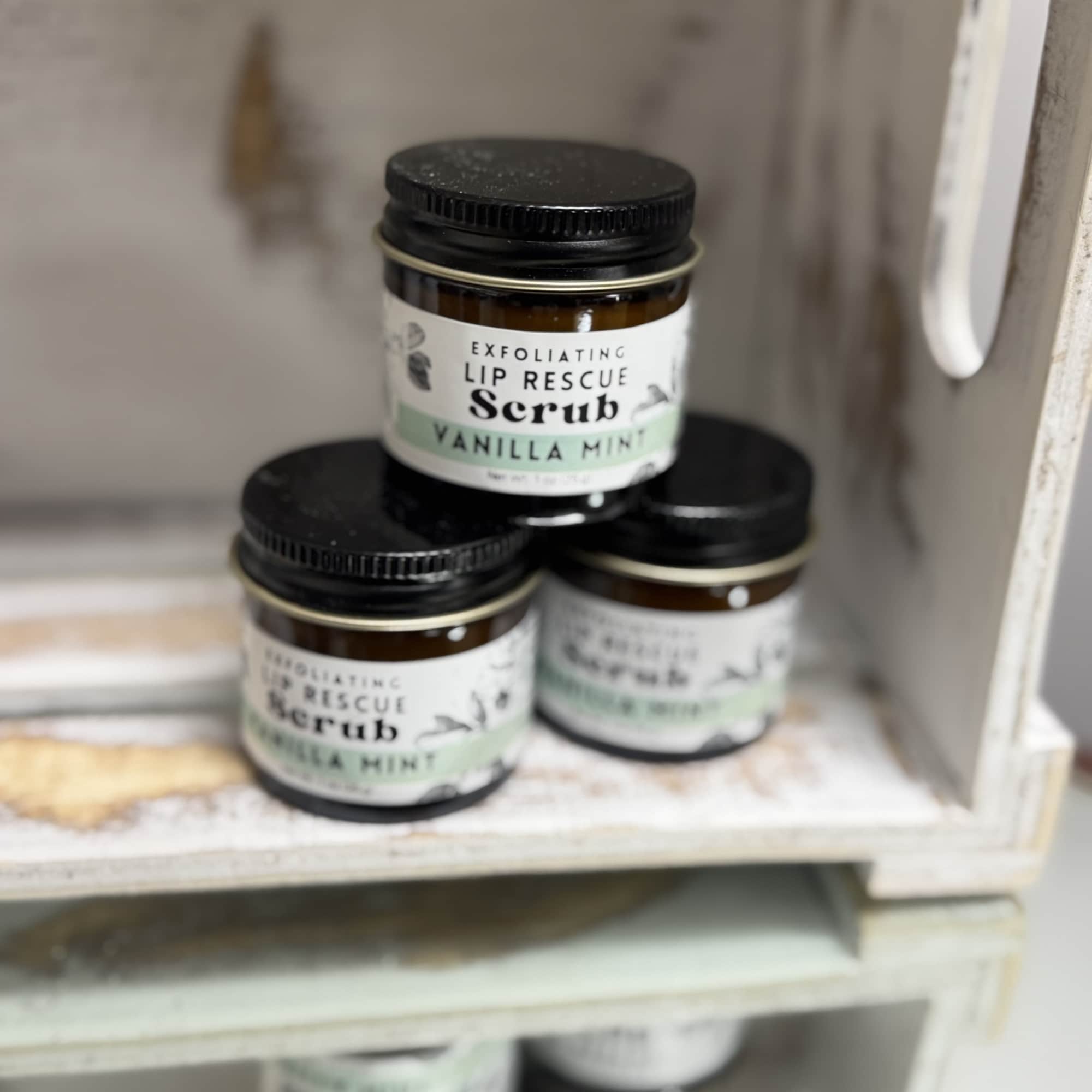 Three jars of vanilla mint lip scrub stacked on a shelf
