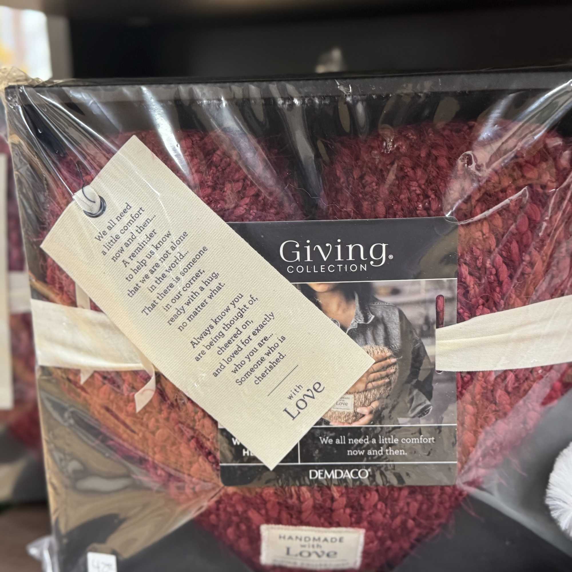 Wrapped burgundy heart-shaped gift with a sympathy tag
