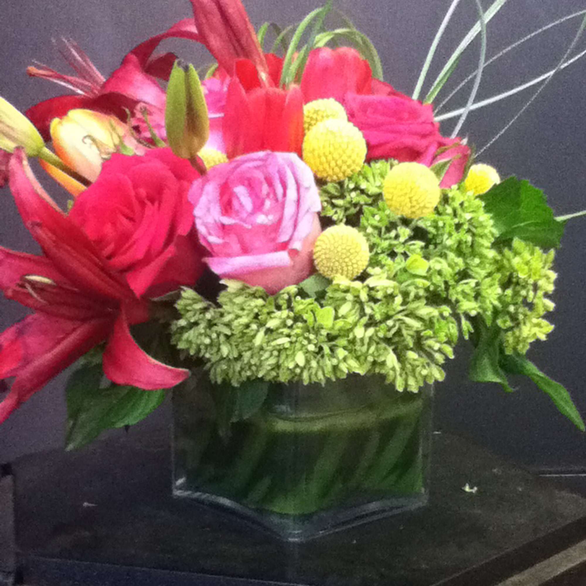 Bright mixed bouquet in a square glass vase with pink and yellow blooms