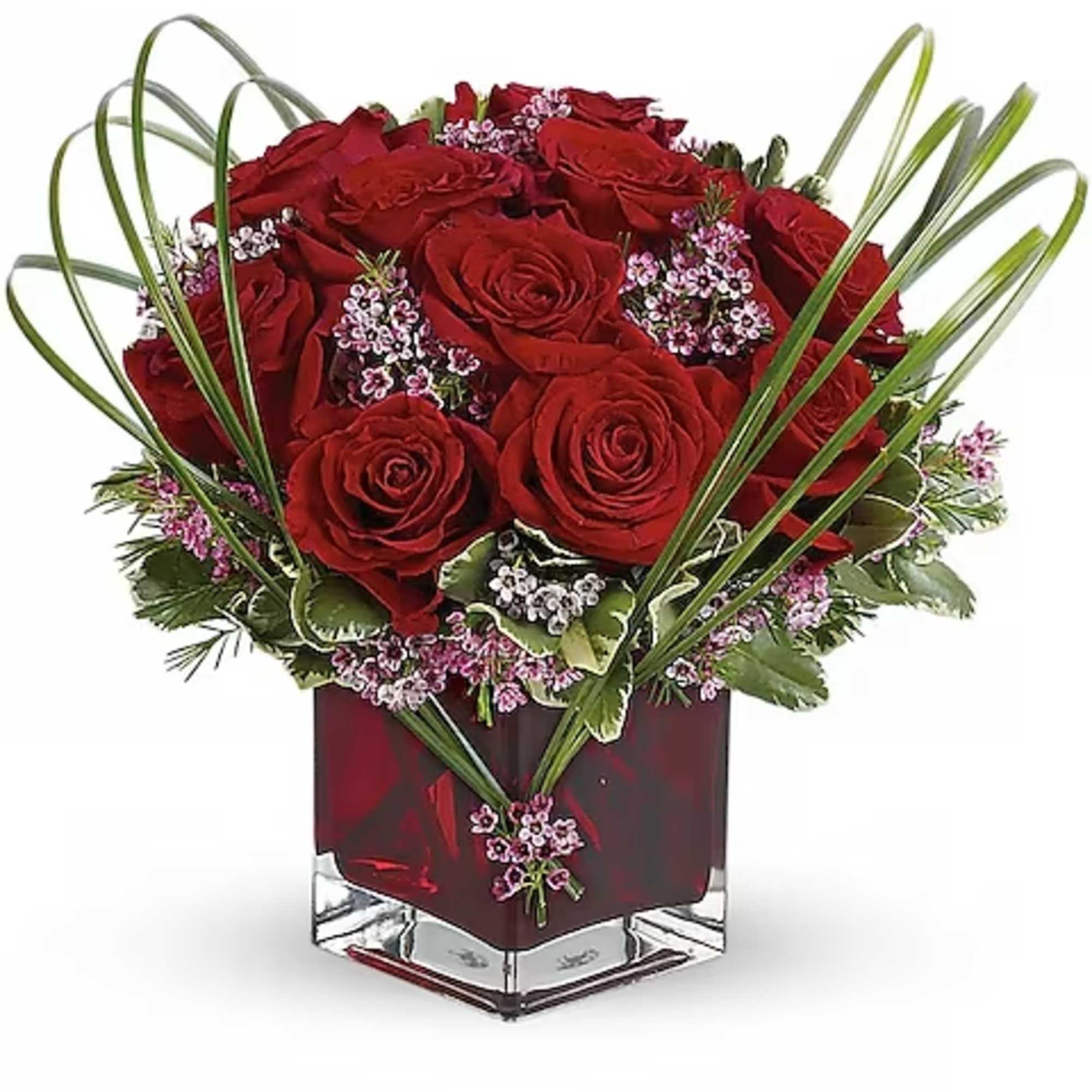 Red roses arranged in a square glass vase with pink filler flowers