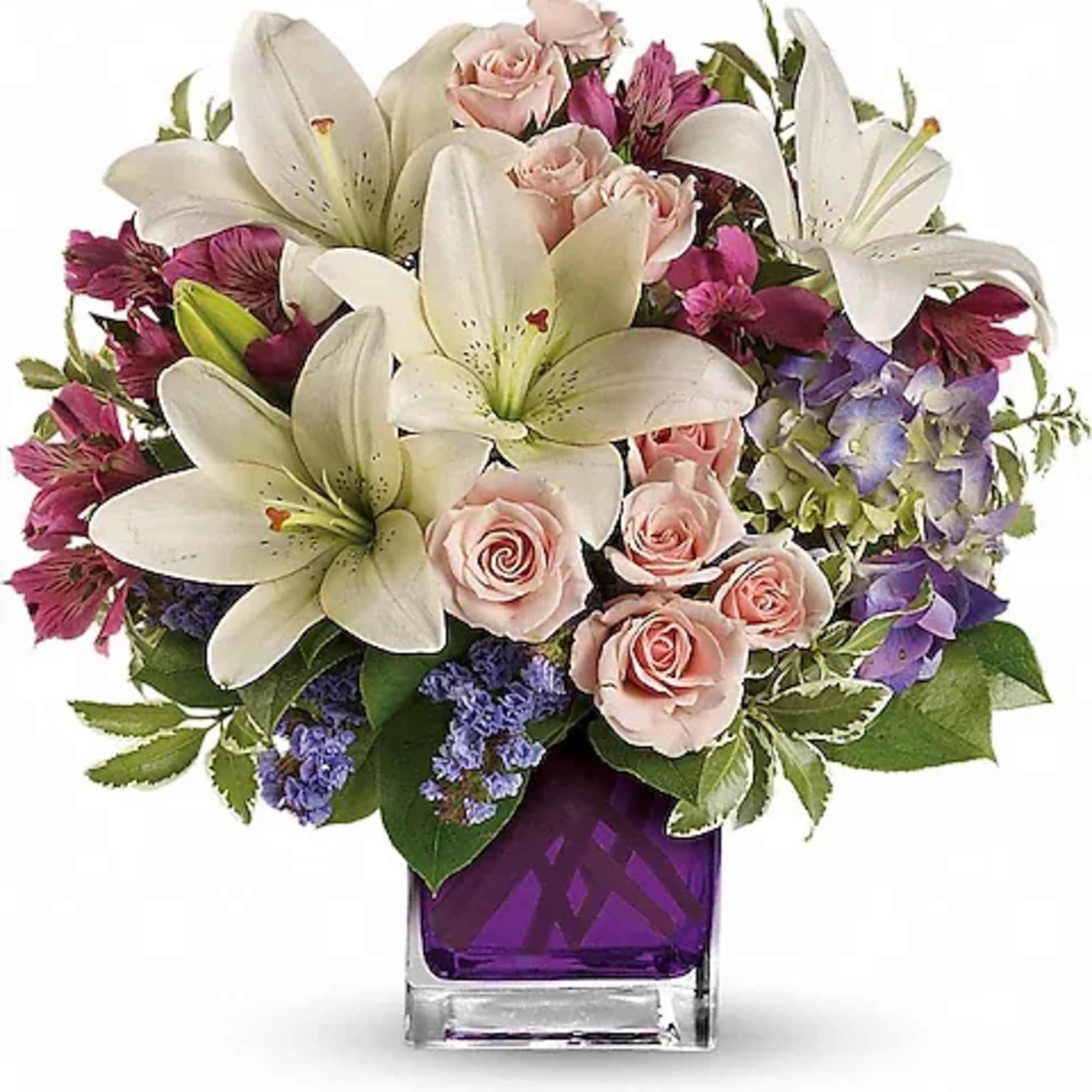 Bouquet of white lilies, pink roses, and purple flowers in a square vase