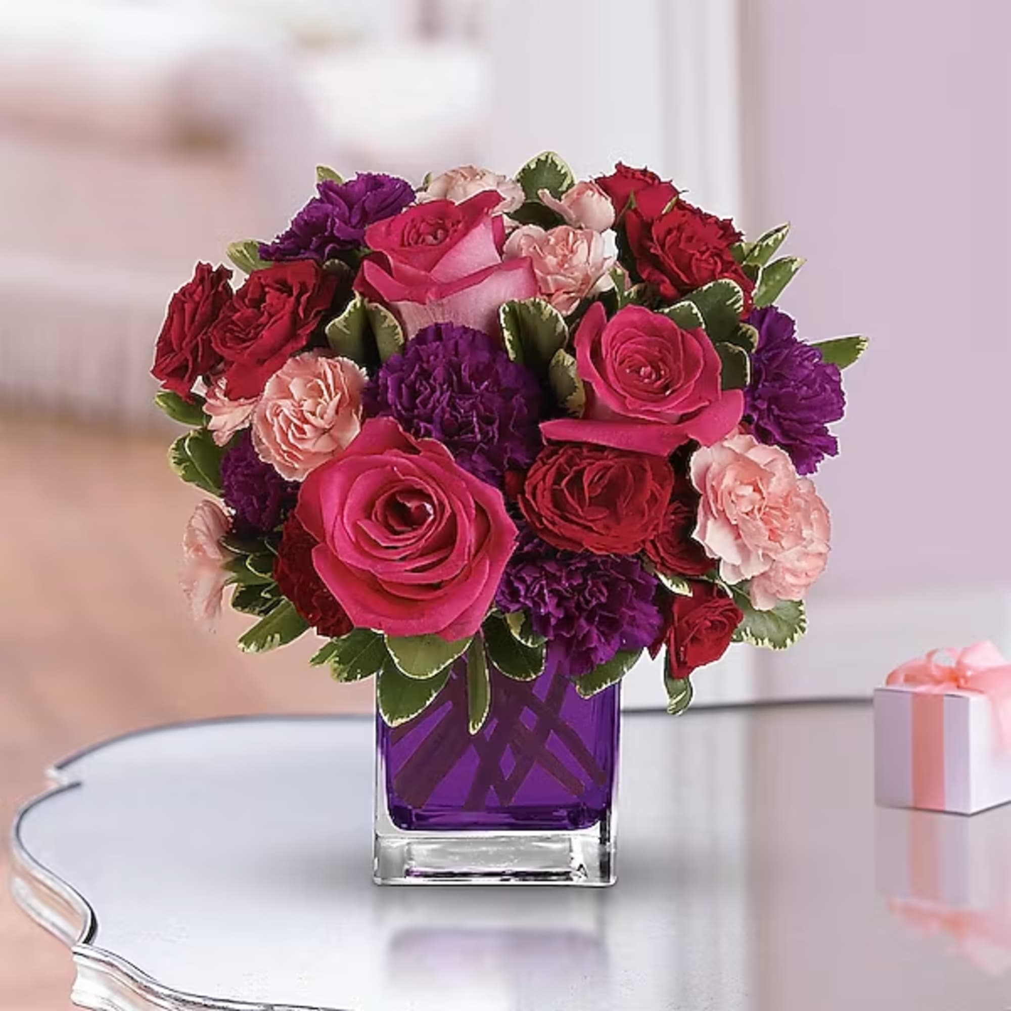 Bouquet of pink, red, and purple roses in a purple glass vase