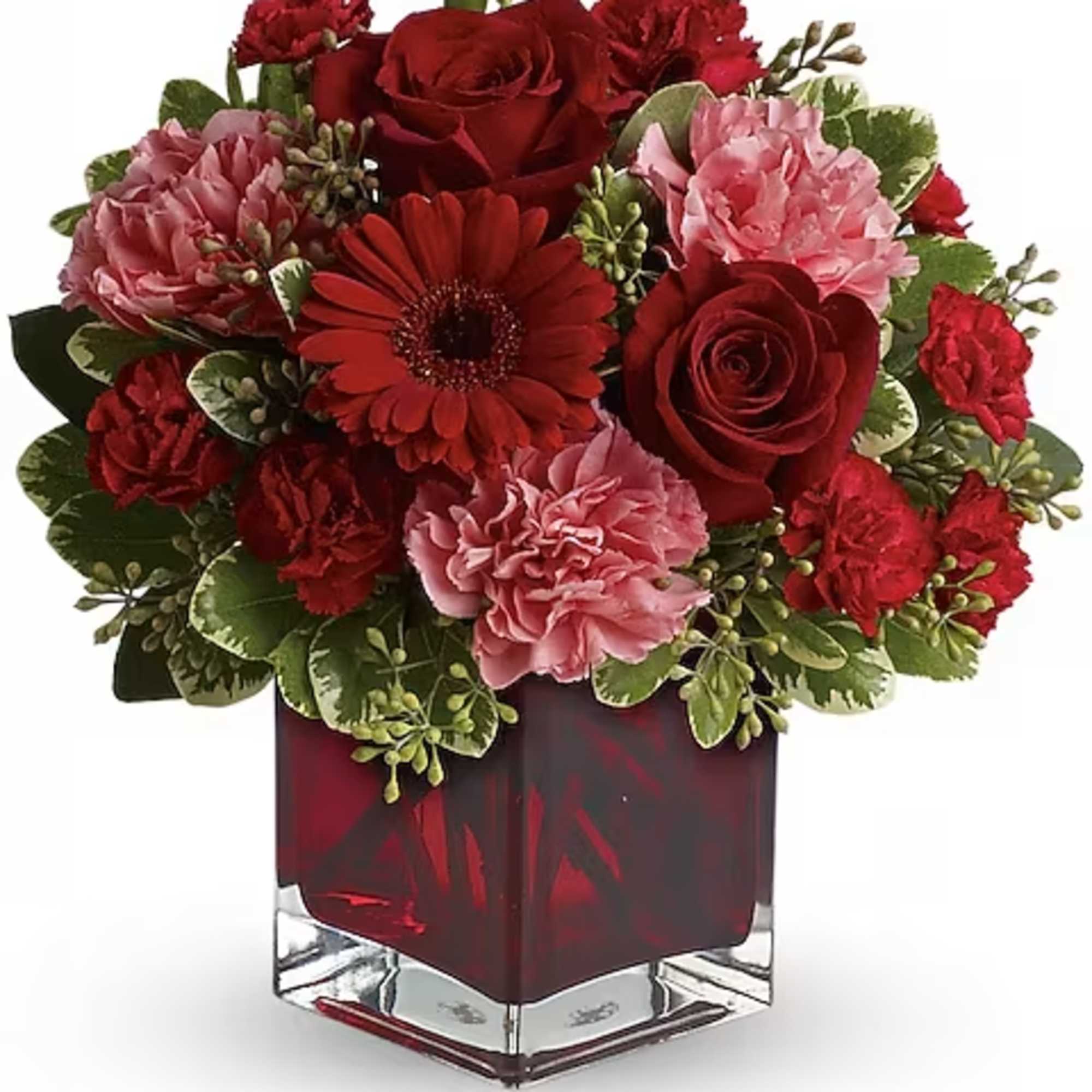 Red and pink floral arrangement in a square glass vase