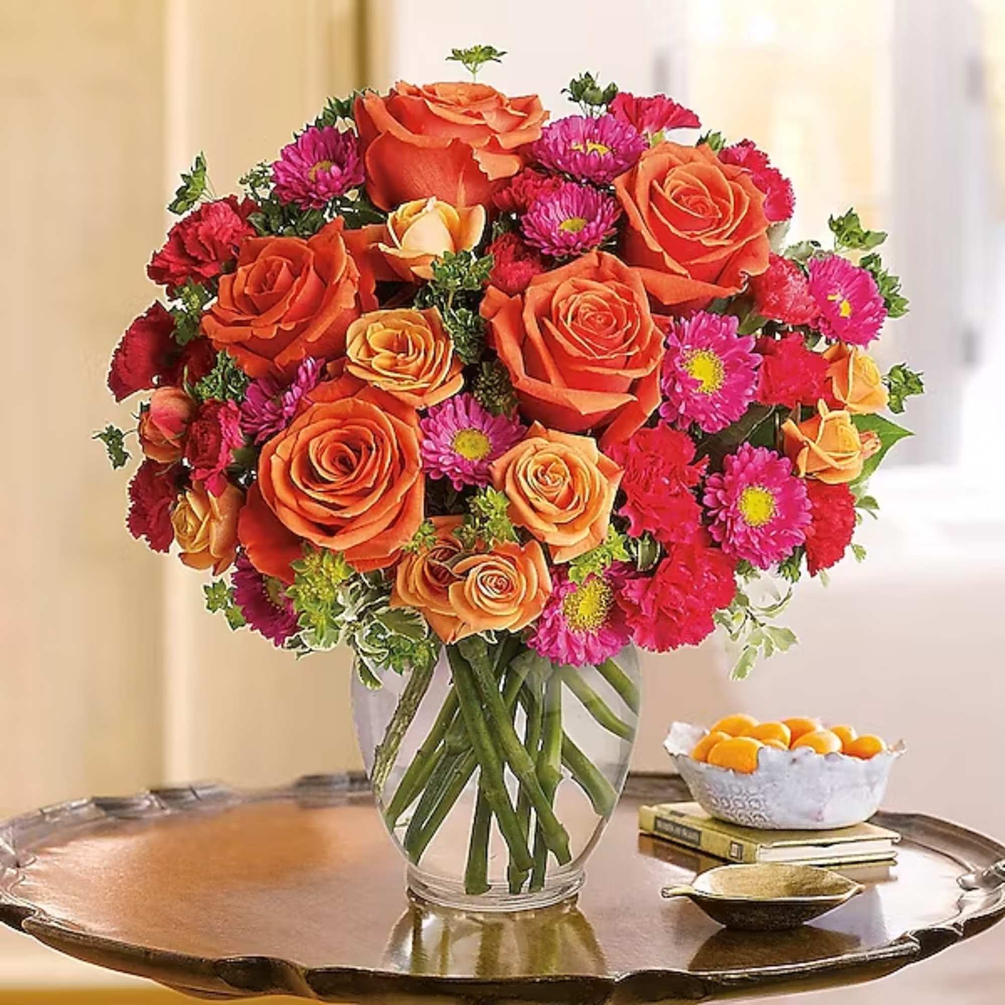 Bouquet of orange roses and pink daisies in a clear glass vase