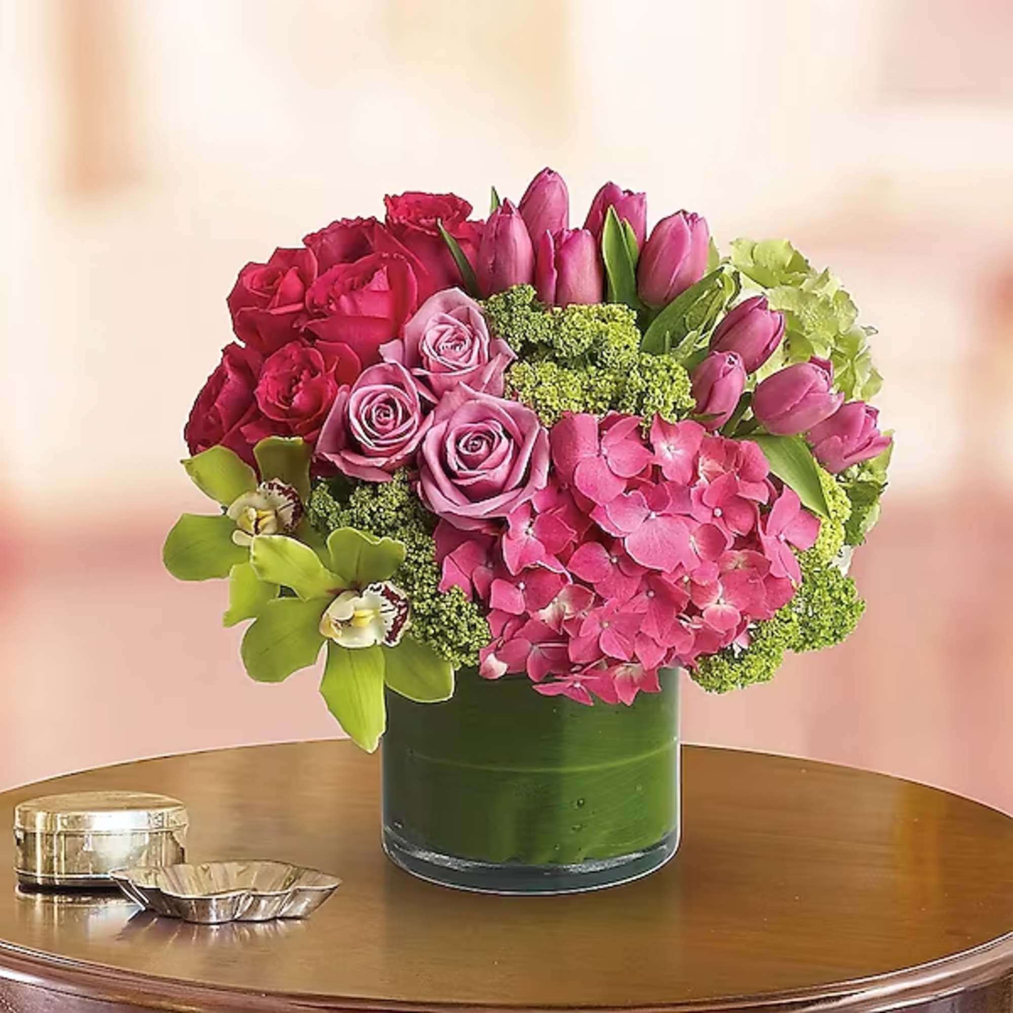 Pink and red flowers arranged in a green glass vase