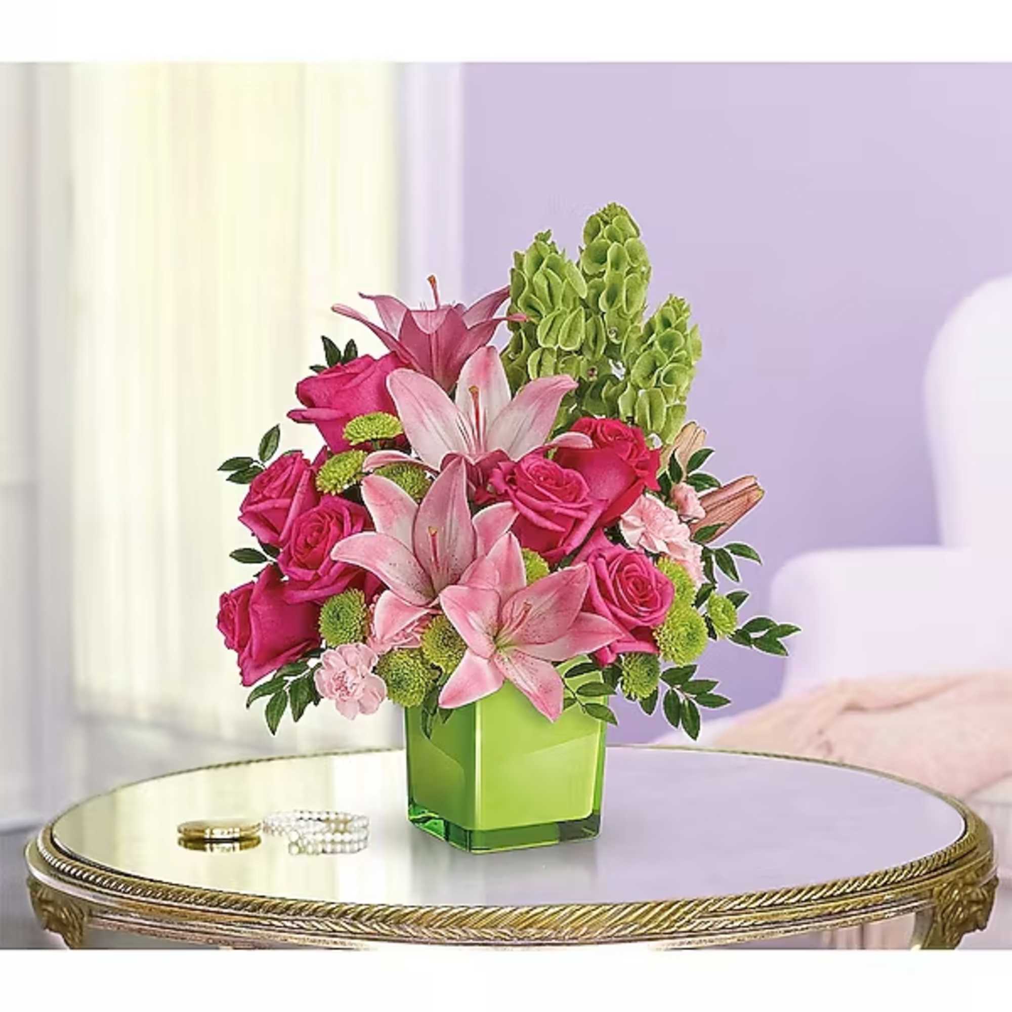 Pink roses and lilies arranged in a green square vase