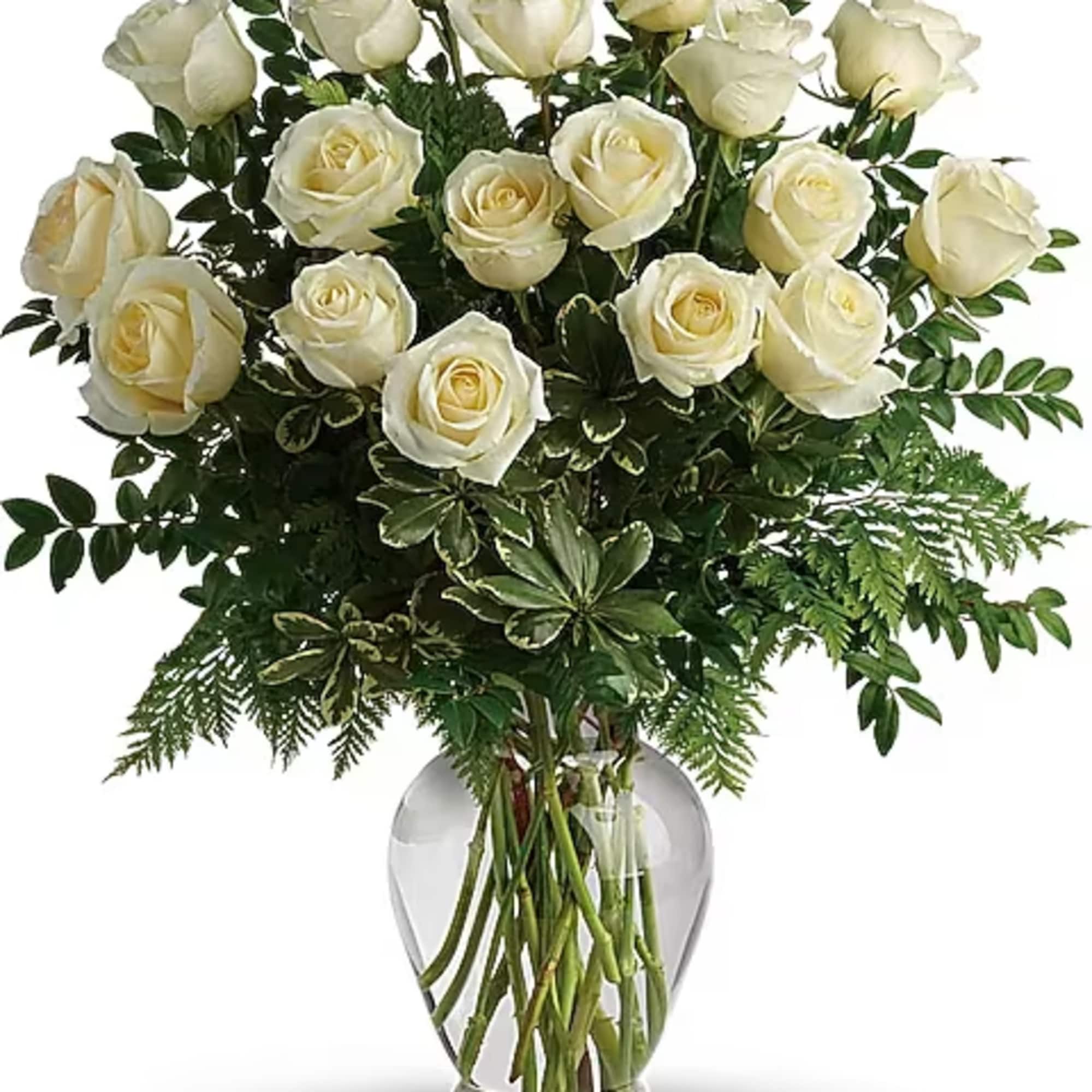 White roses arranged in a clear glass vase with greenery