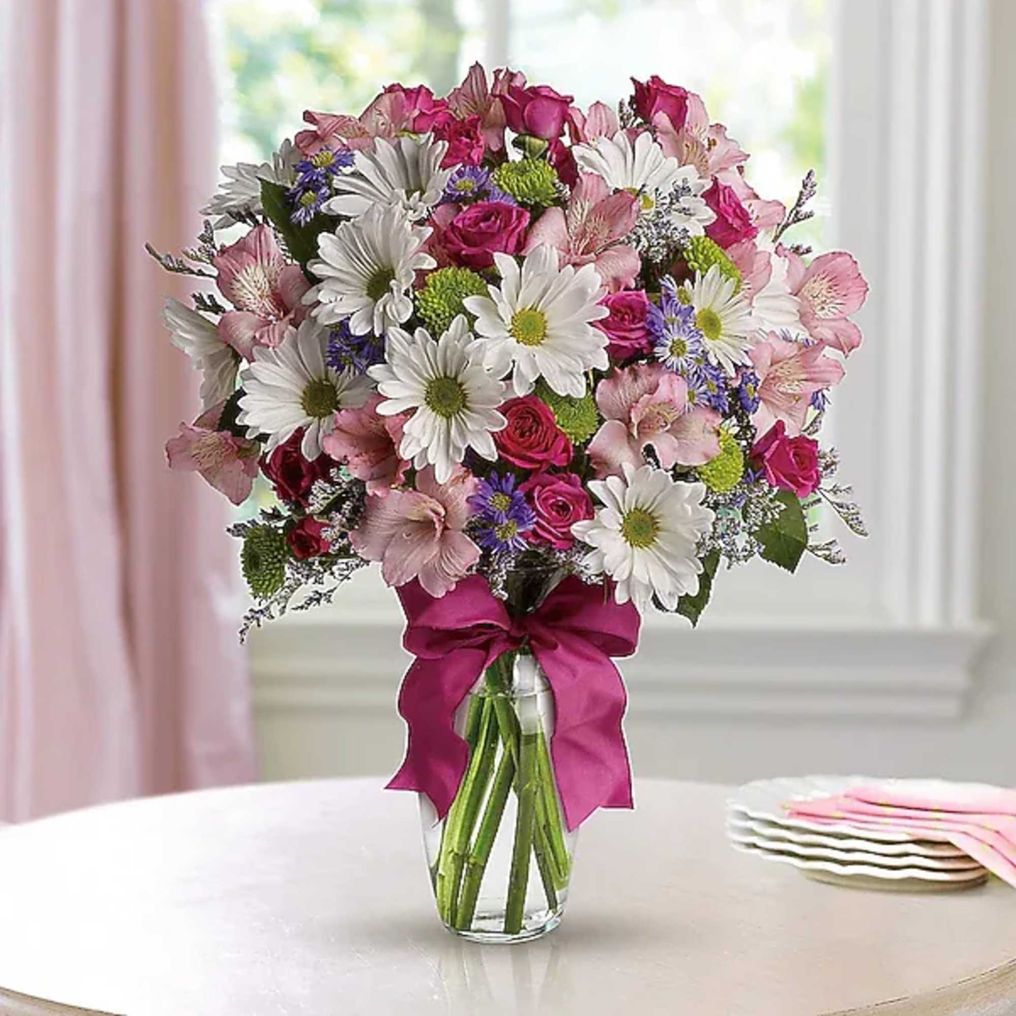 Mixed bouquet of pink roses, white daisies, and alstroemeria in a glass vase