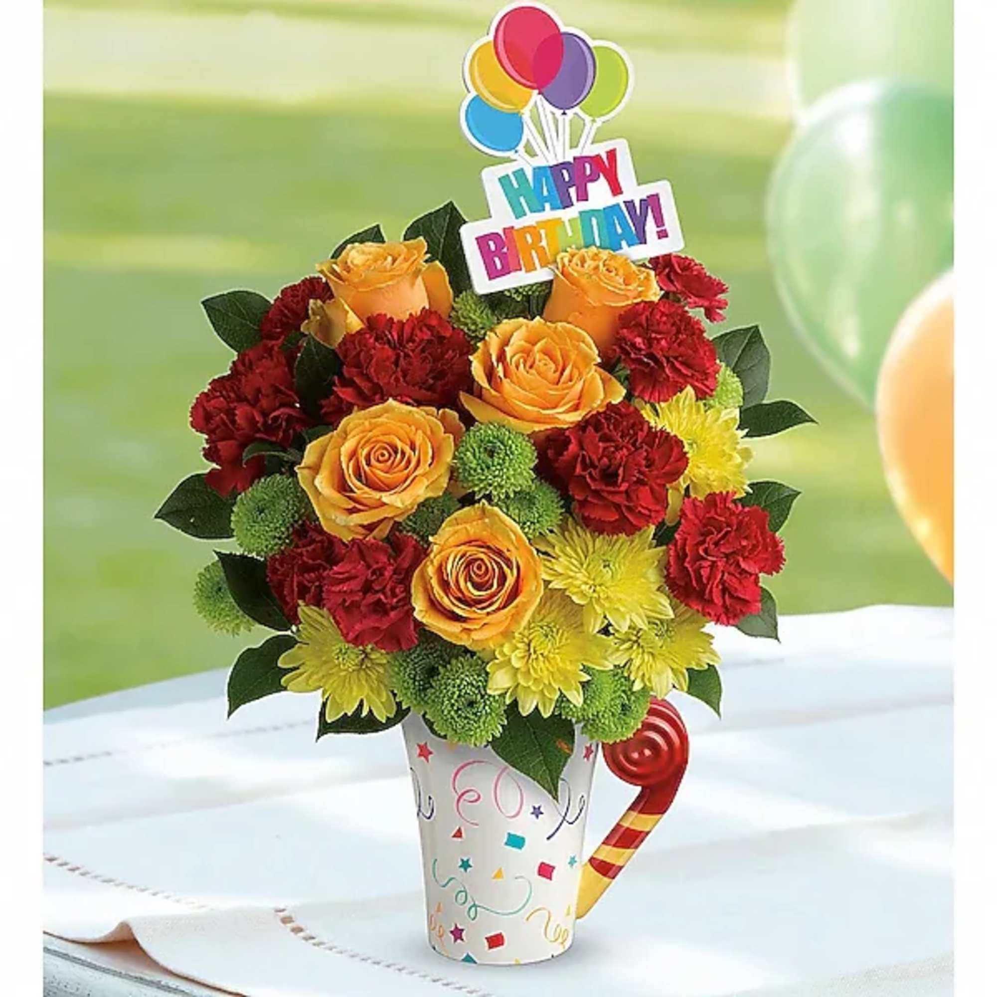 Birthday bouquet of orange roses, red carnations, and yellow mums in a party cup