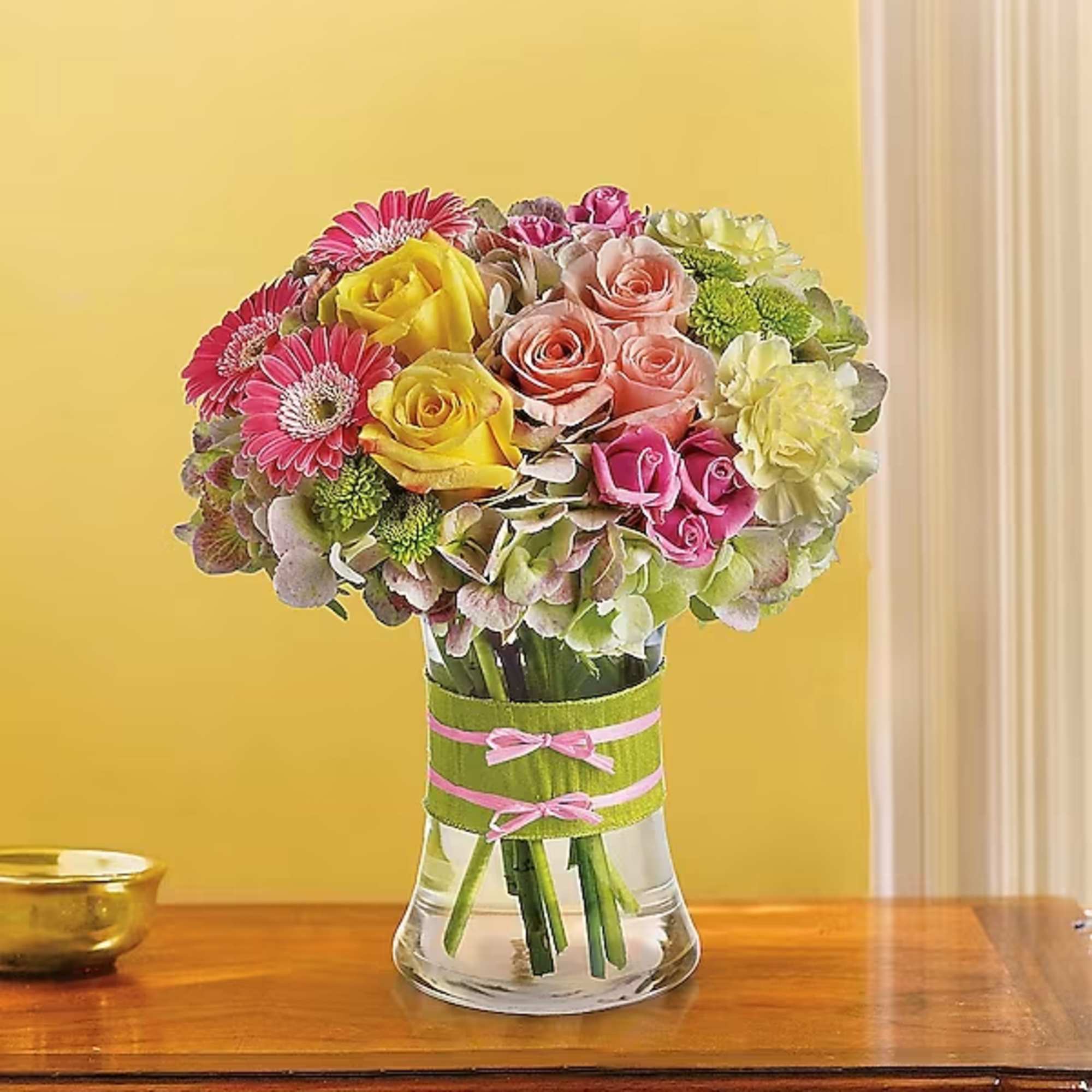 Mixed bouquet of roses and gerbera daisies in a glass vase