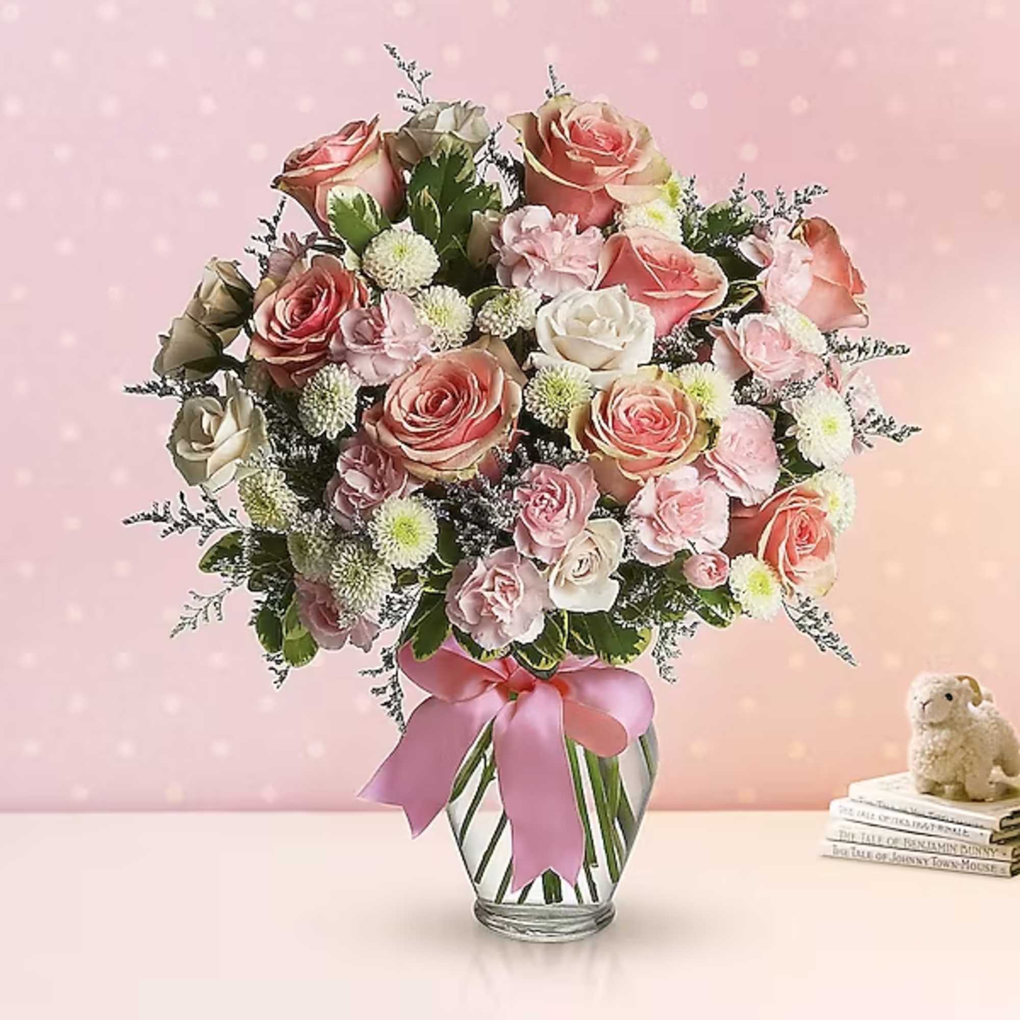 Pink and white rose bouquet in a glass vase with a ribbon