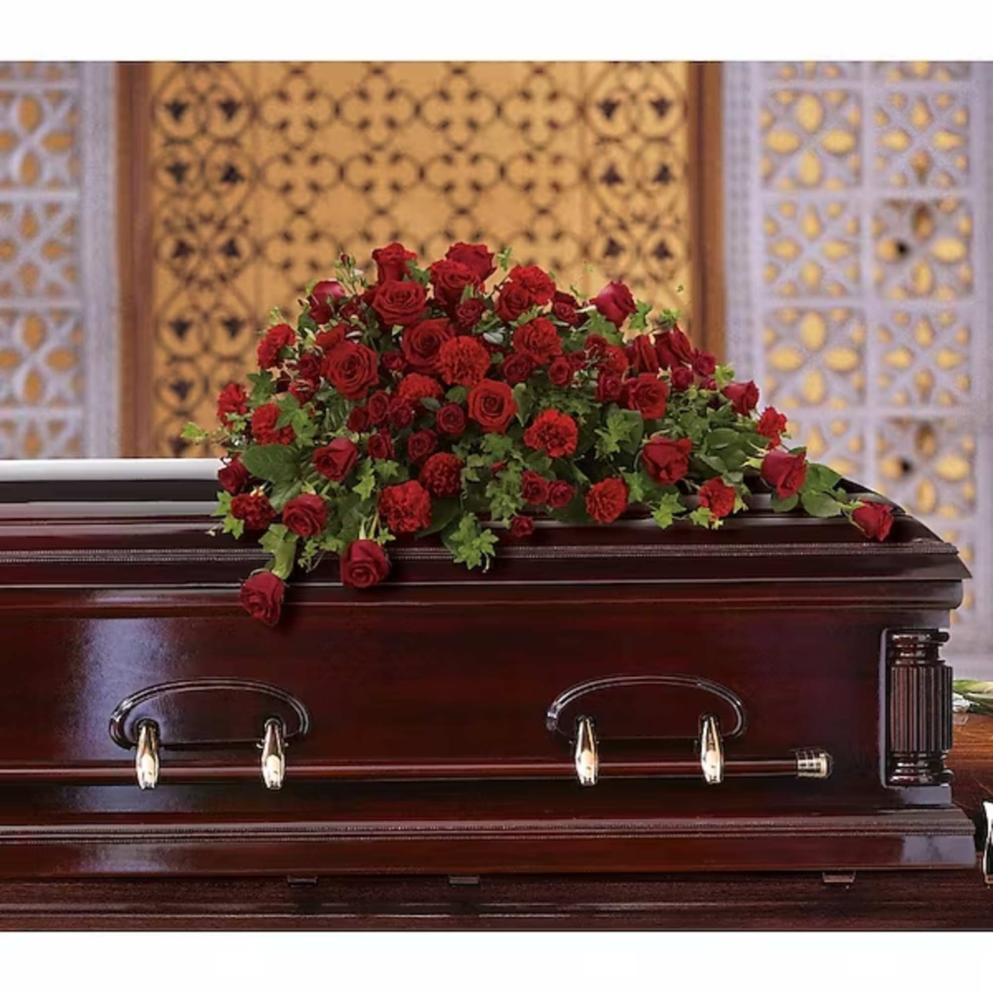 Red rose casket spray on a dark wood coffin