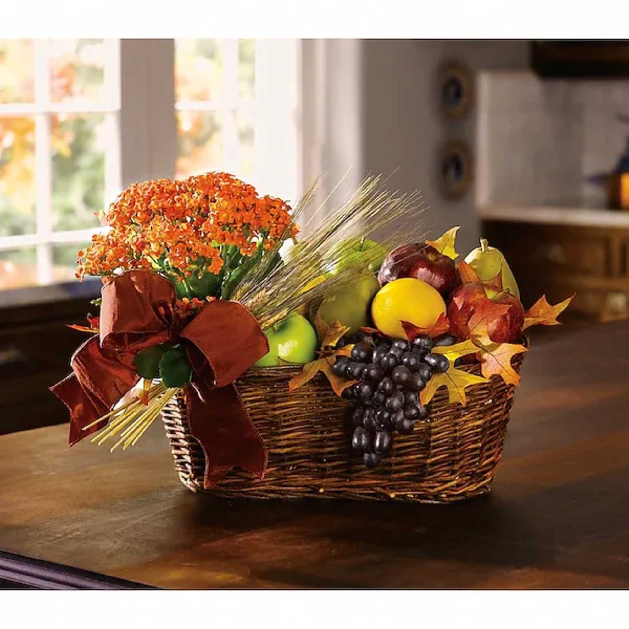 Autumn basket with orange flowers, fruit, and a burgundy ribbon