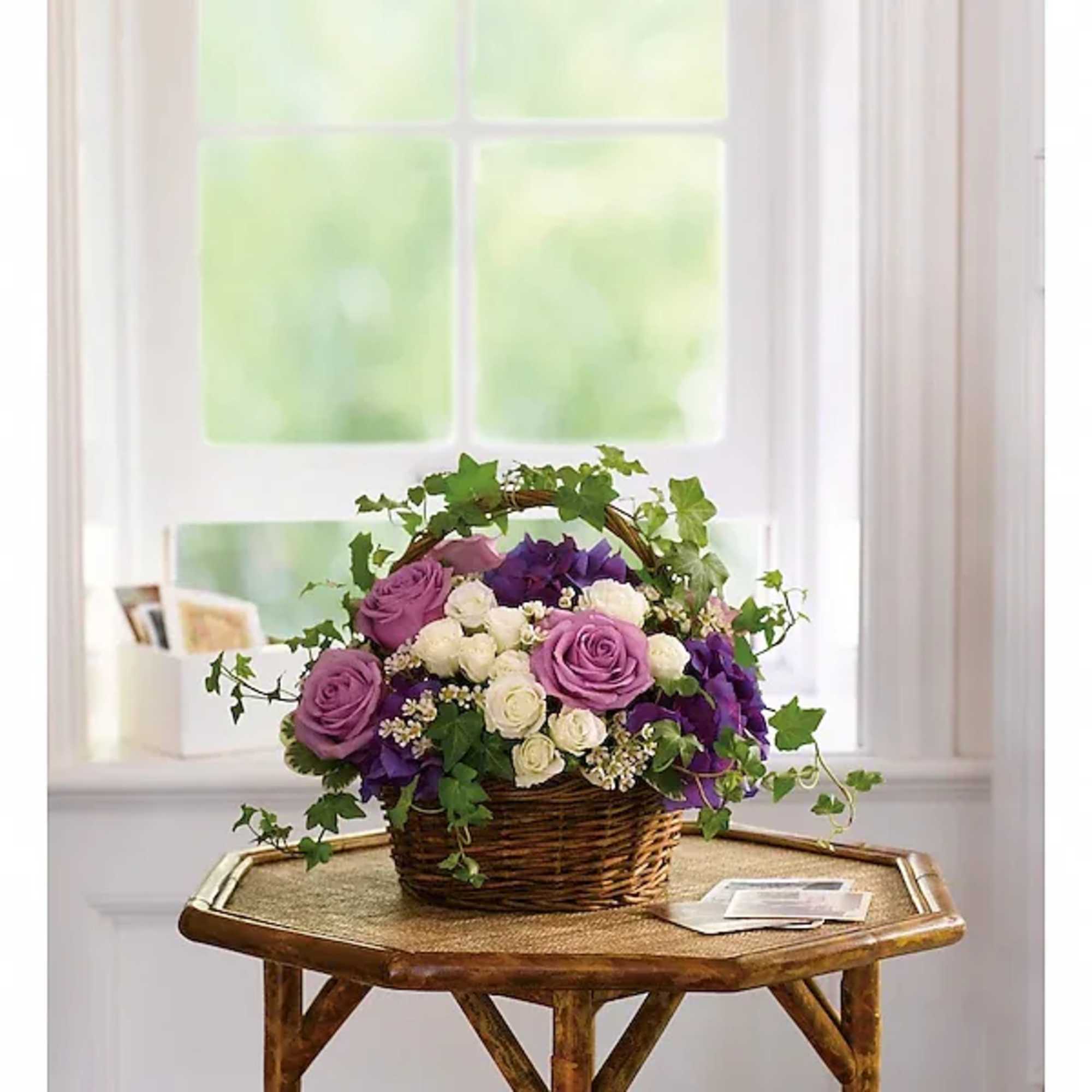 Purple and white roses in a wicker basket with ivy