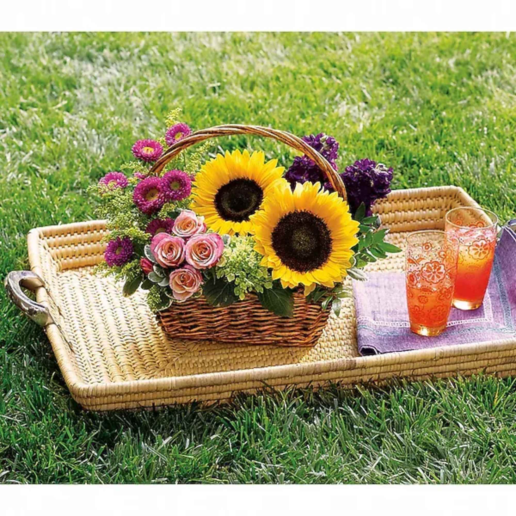 Basket of sunflowers, pink roses, and purple flowers on a picnic tray