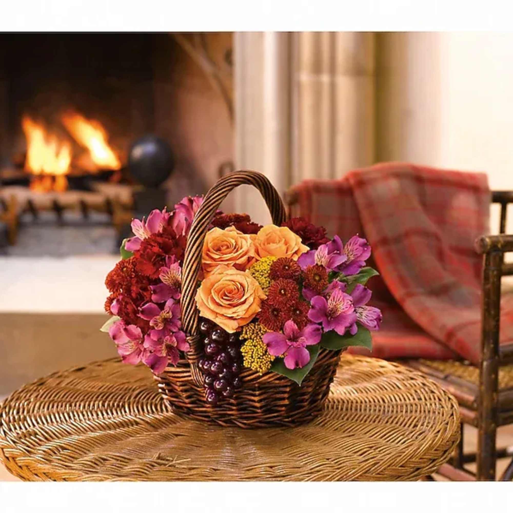 Basket of orange roses and purple flowers on a wicker table