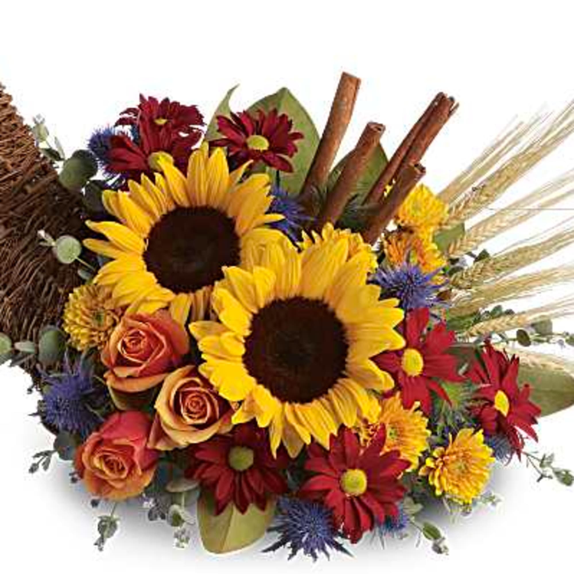 Sunflowers and mixed blooms arranged with wheat and cinnamon sticks in a wicker cornucopia
