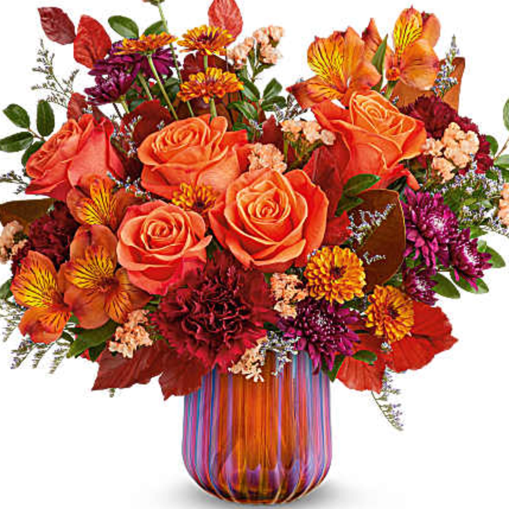 Orange roses and mixed fall flowers in a striped glass vase