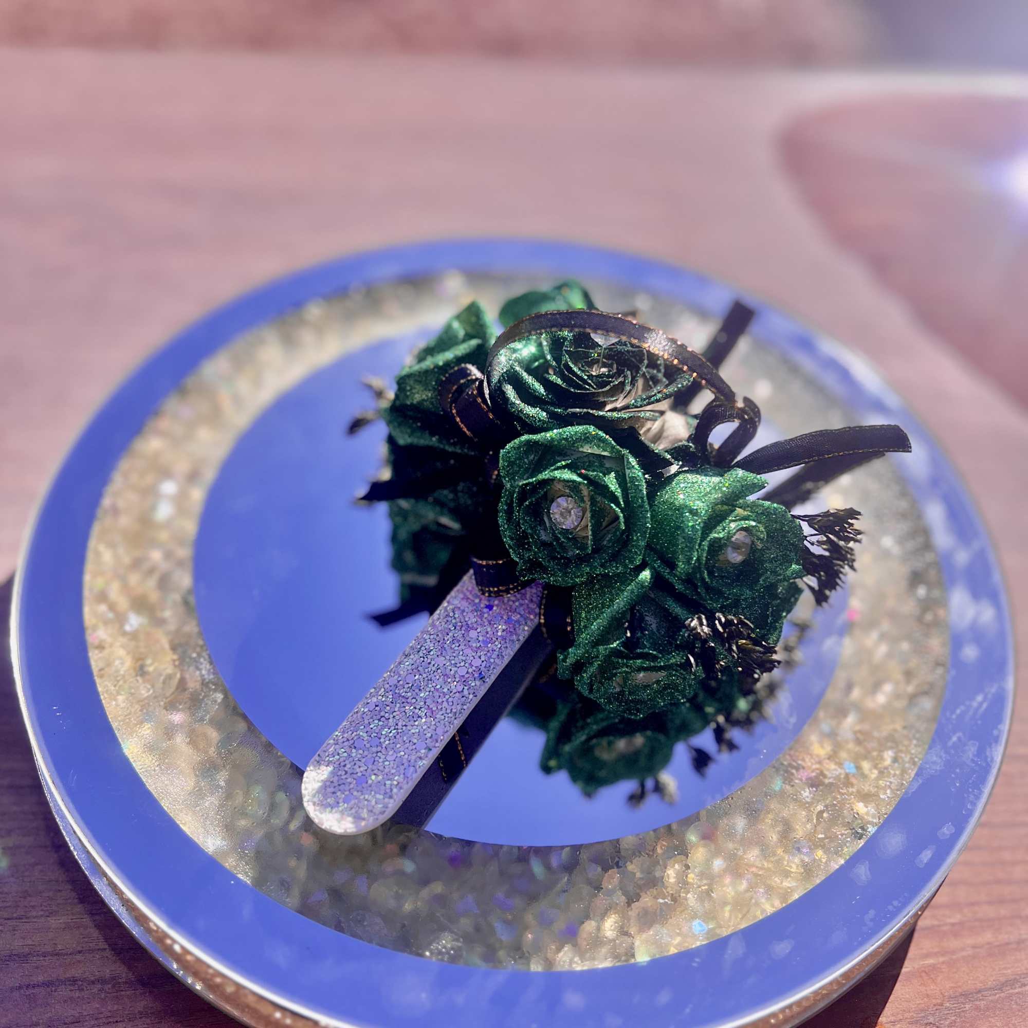 Small glittery green rose corsage on a blue circular box
