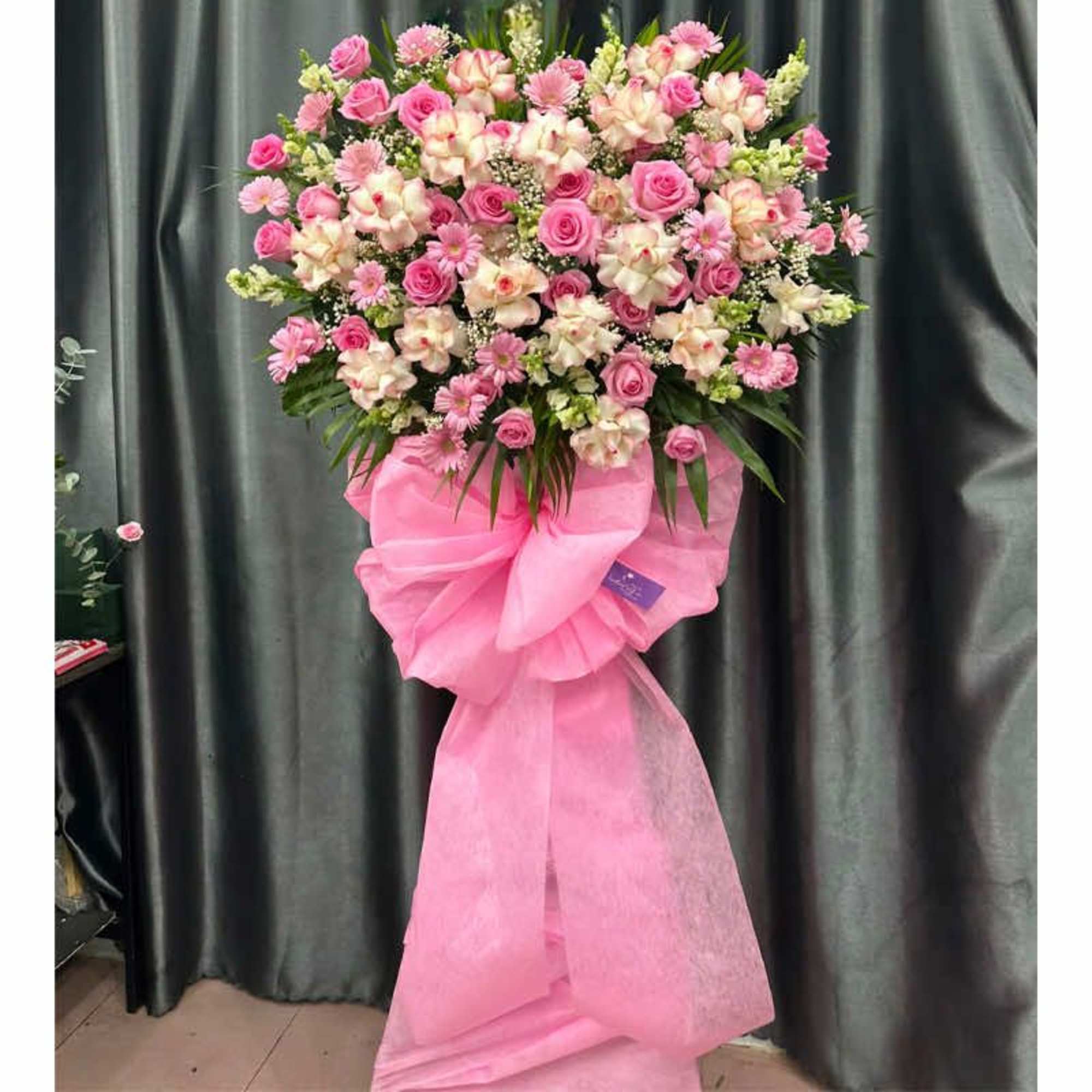Pink and white floral standing spray with a large pink bow