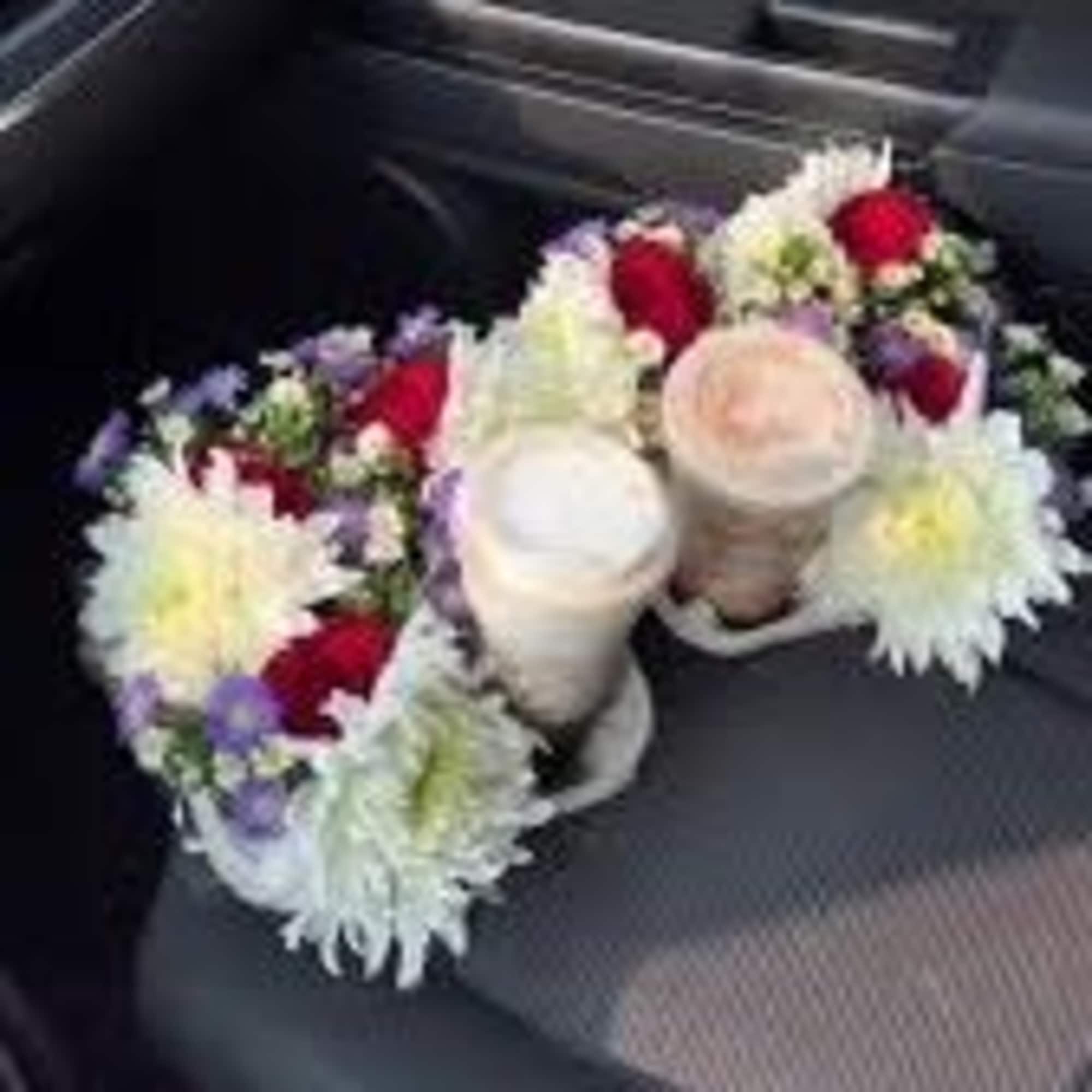 Two floral arrangements with white and red blooms on car seats