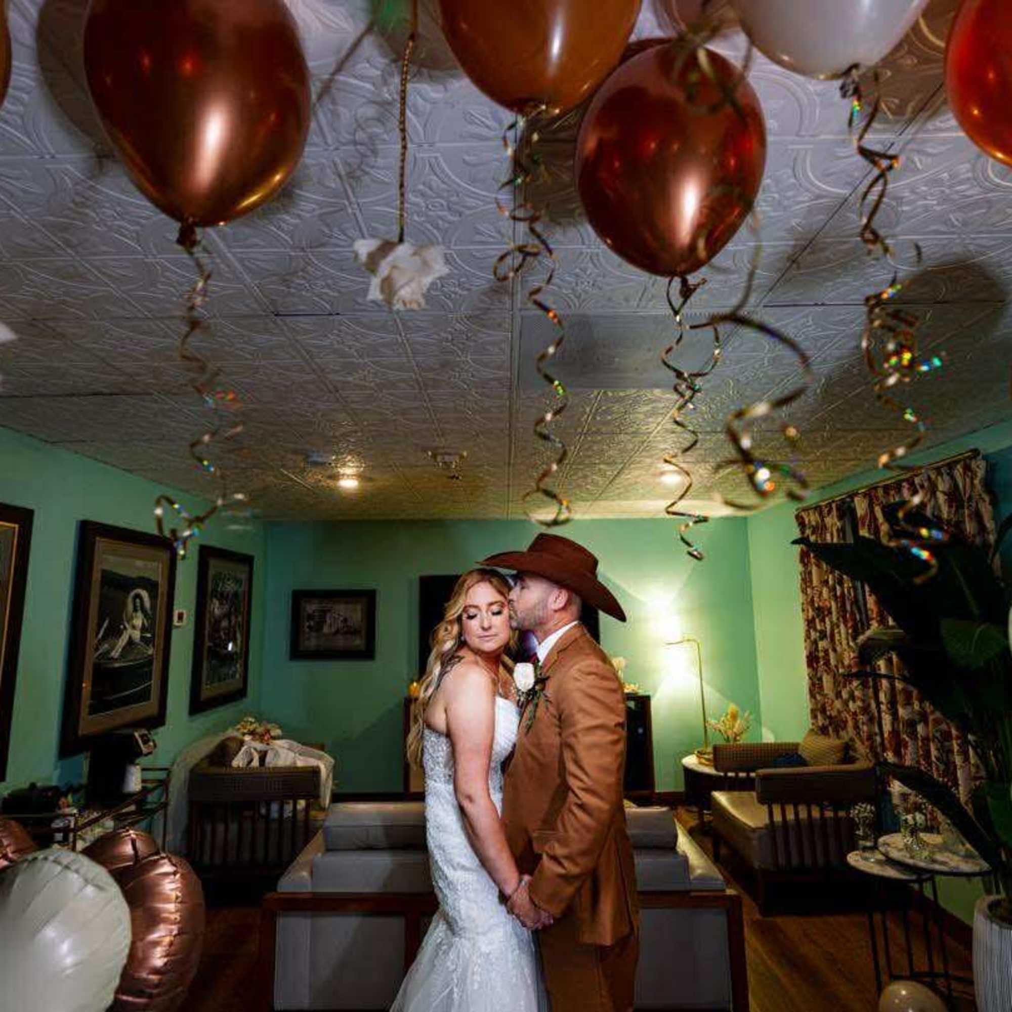 Bride and groom posing in a room decorated with balloons and streamers