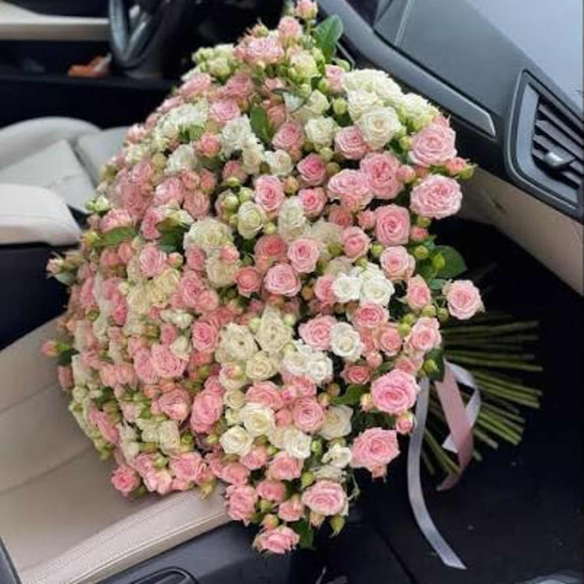 Large bouquet of pink and white spray roses in a car seat