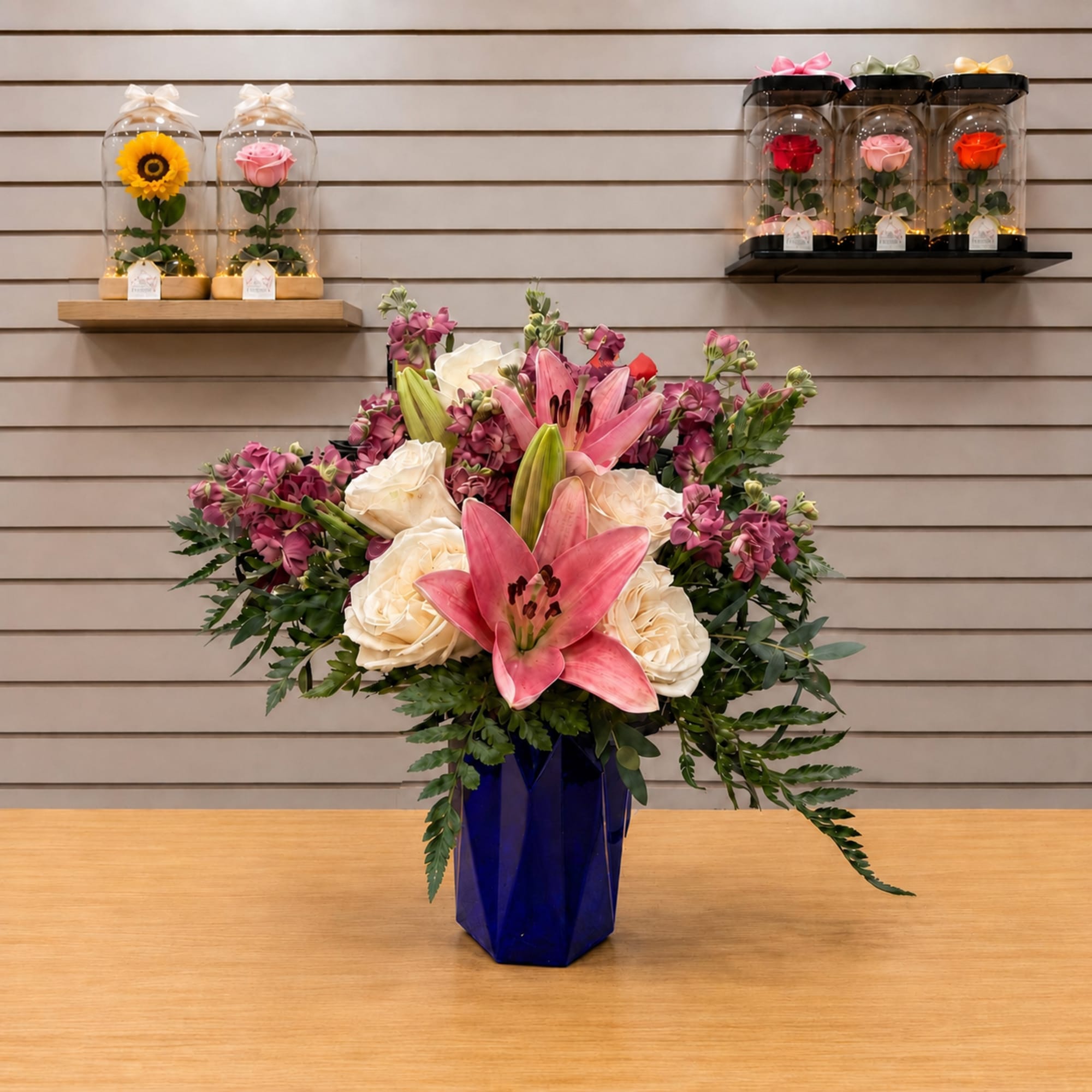 Pink lilies and cream roses arranged in a blue vase