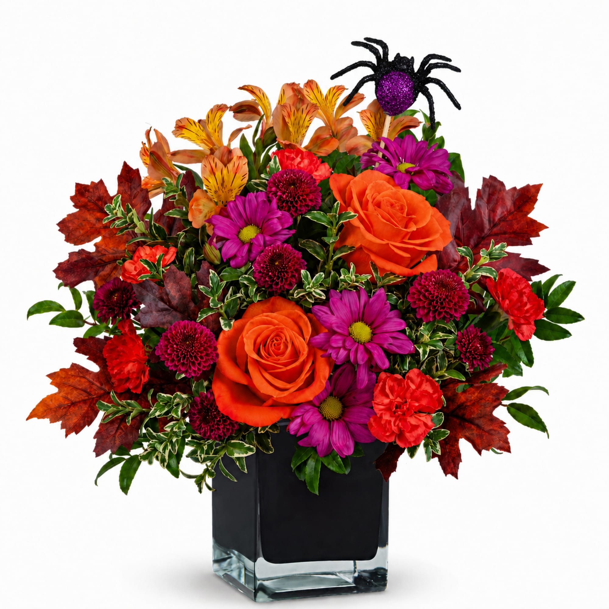 Orange and purple floral arrangement in a square glass vase with a glitter spider pick