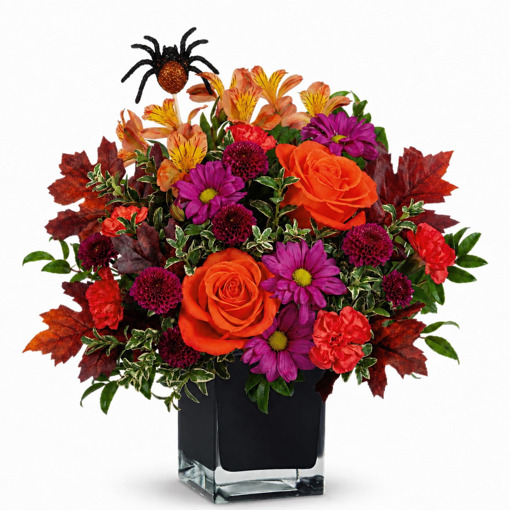 Orange roses and purple daisies in a square glass vase with autumn leaves
