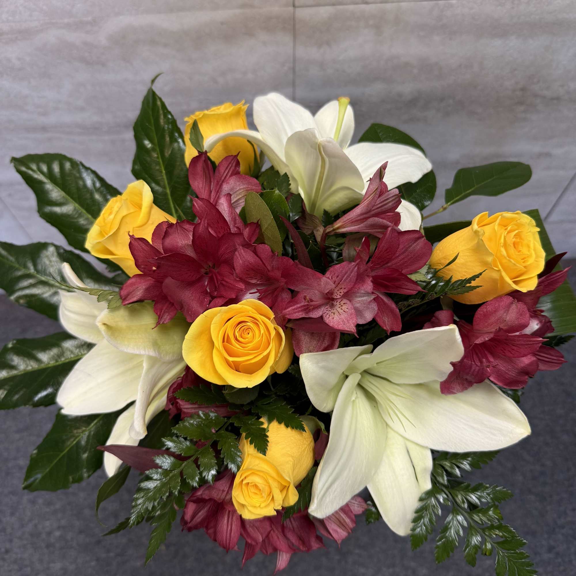 Bouquet of yellow roses, white lilies, and burgundy alstroemeria