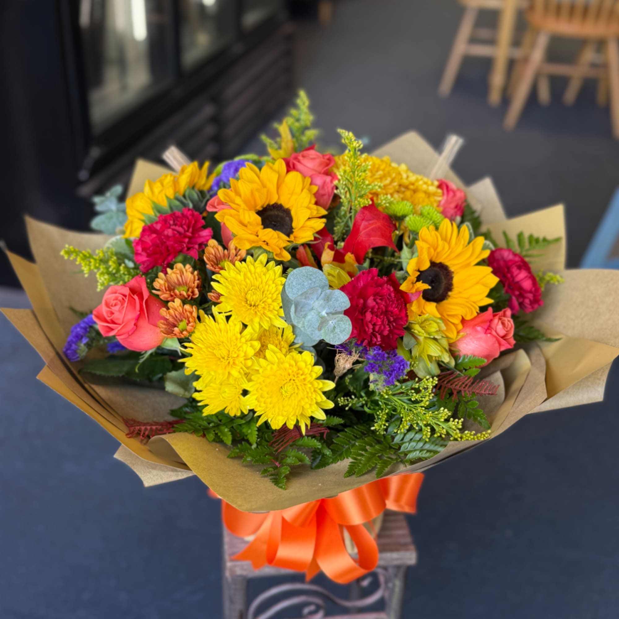 Mixed bouquet with sunflowers, roses, and chrysanthemums wrapped in paper
