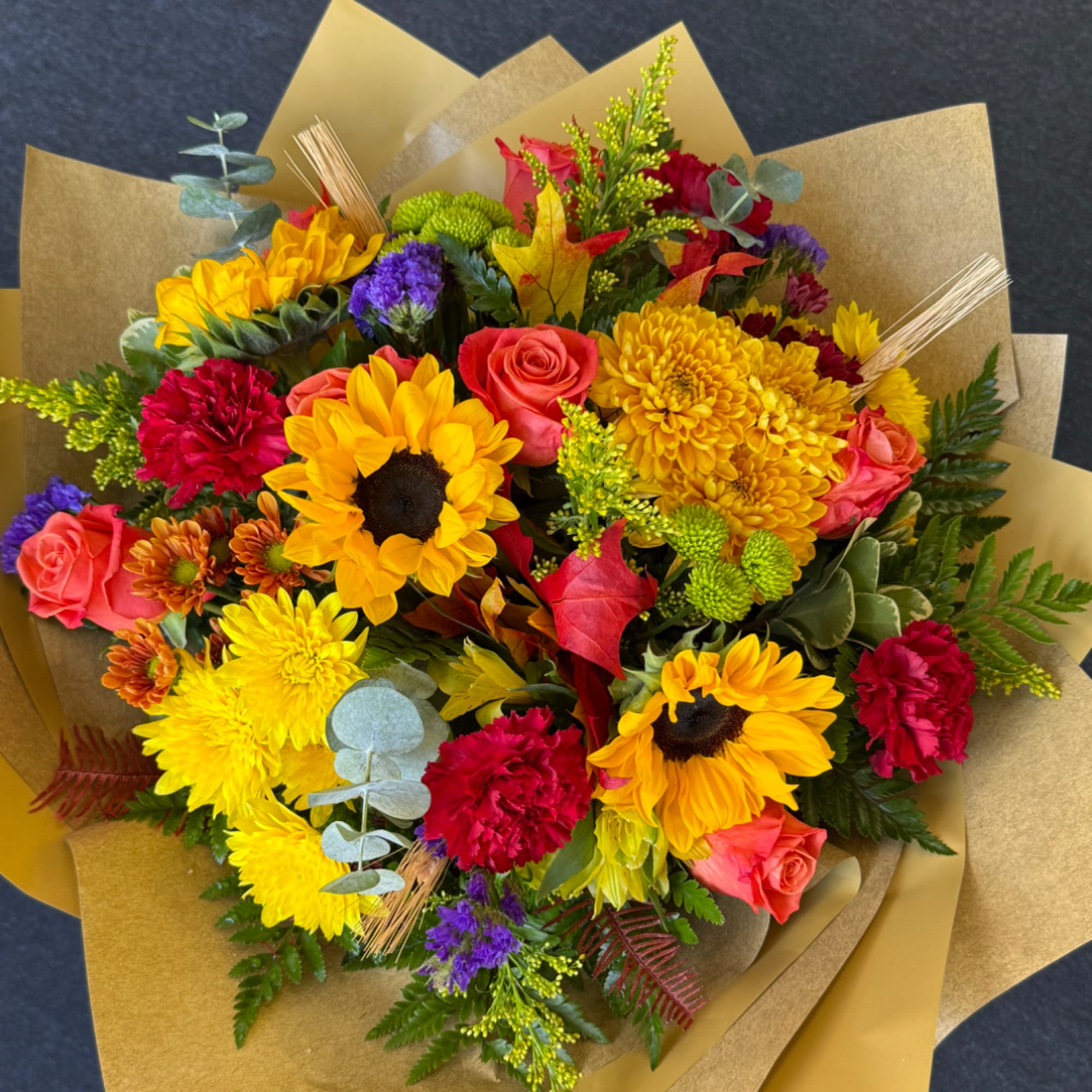 Colorful bouquet with sunflowers, roses, and chrysanthemums wrapped in gold paper