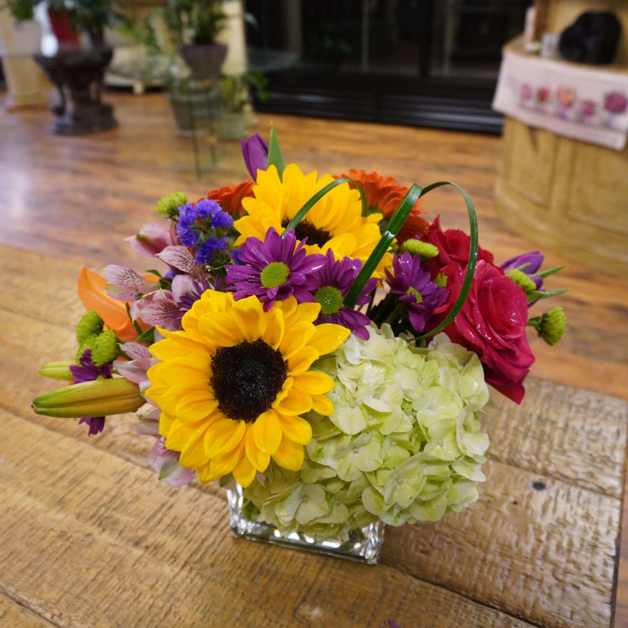 Colorful mixed bouquet in a square glass vase with sunflowers and roses