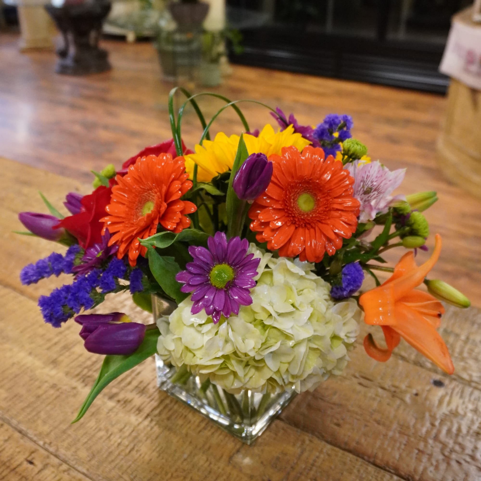 Colorful mixed bouquet in a square glass vase with gerbera daisies and lilies