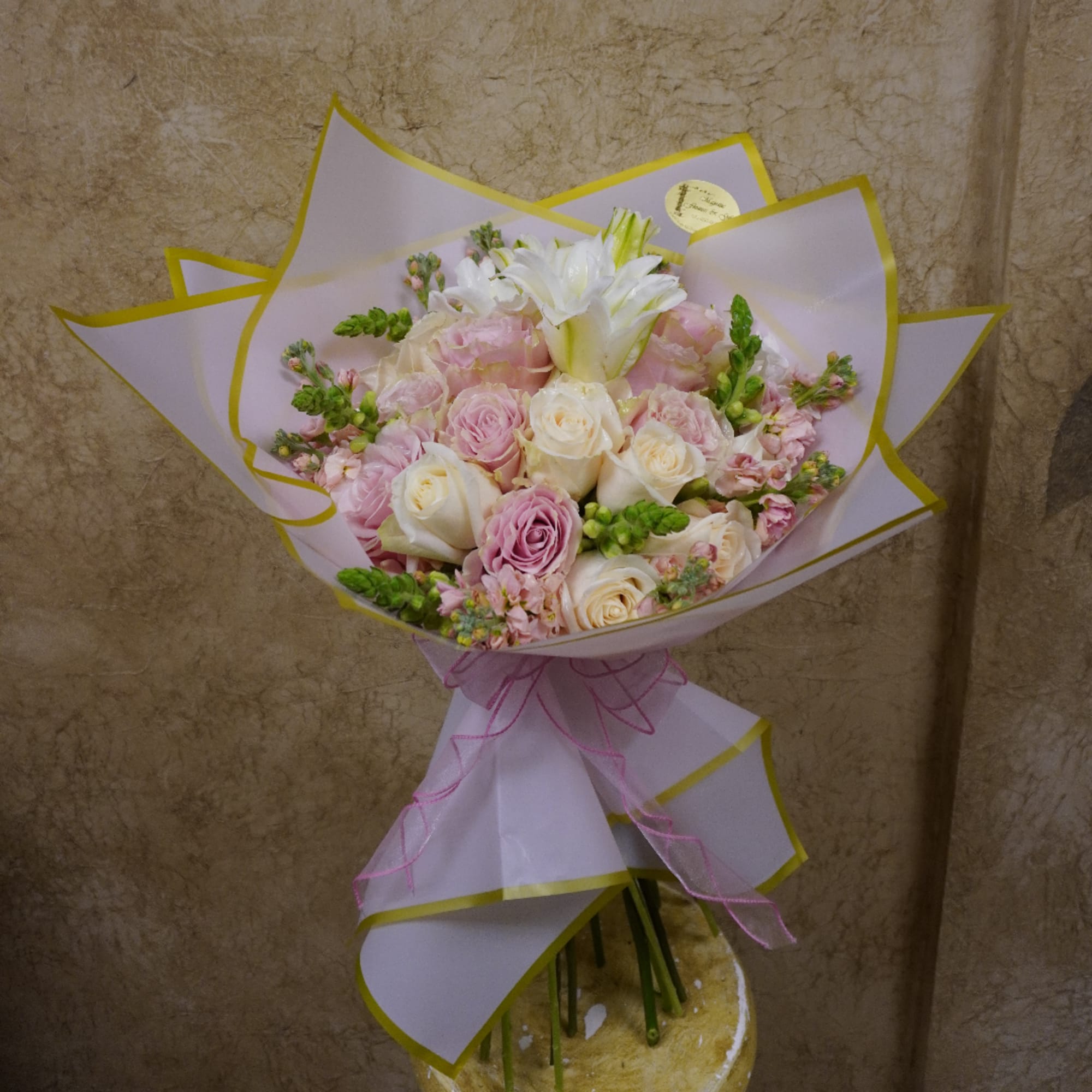 Pink and white rose bouquet wrapped in pale paper with a ribbon