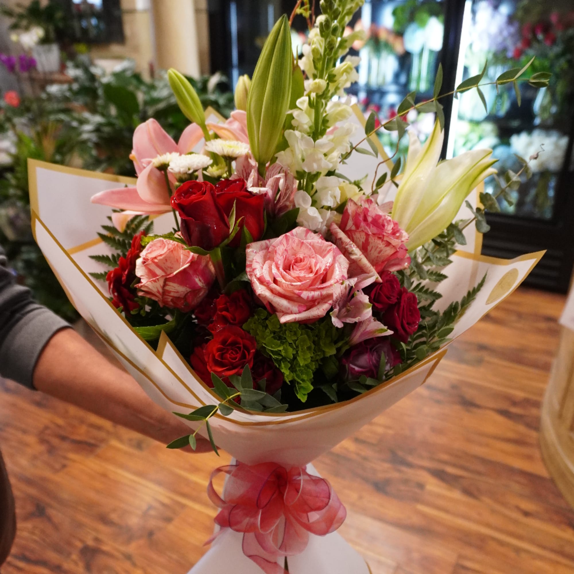 Bouquet of red and pink roses with lilies wrapped in white paper